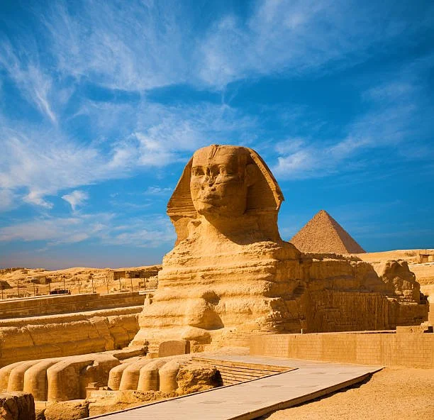 Great Sphinx and Pyramid of Khafre at Giza under a blue sky.