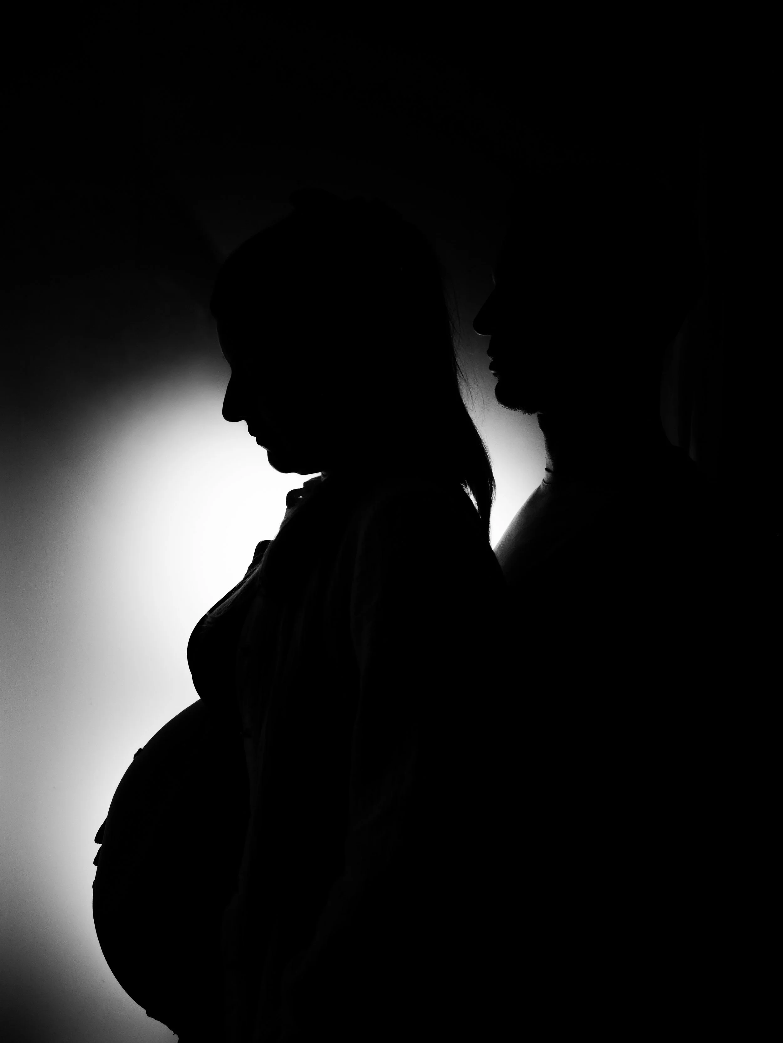 Silhouettes d'un homme et d'une femme, face à face, en profil, avec un fond lumineux derrière eux.