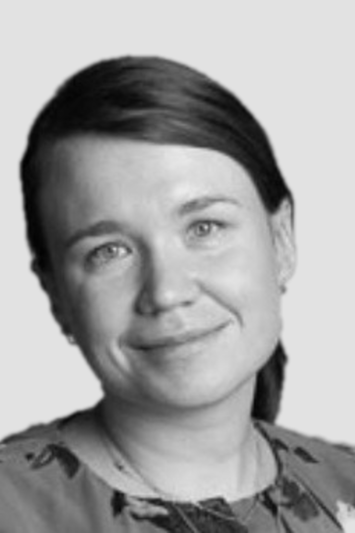 Black and white portrait of a woman with straight dark hair, smiling, wearing a patterned top.