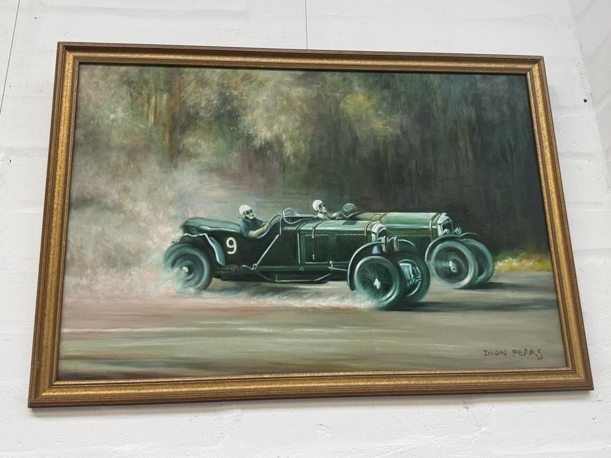 Painting of vintage race cars, signed by Dion Bears, with three drivers in helmets and goggles driving through a forested landscape.