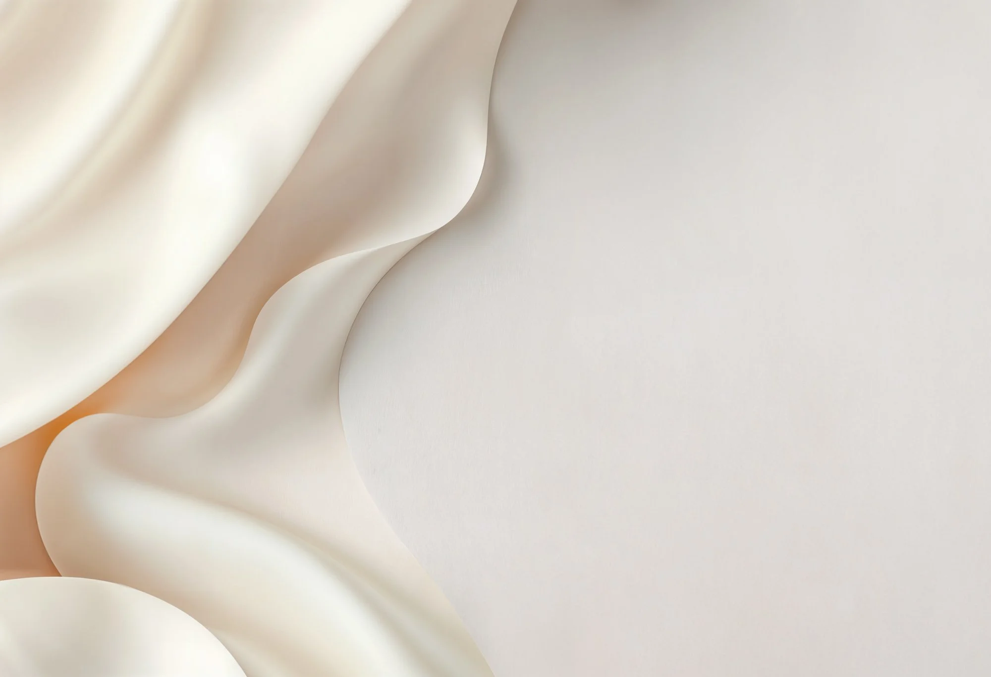 Close-up of smooth, white, flowing fabric with soft folds and curves.