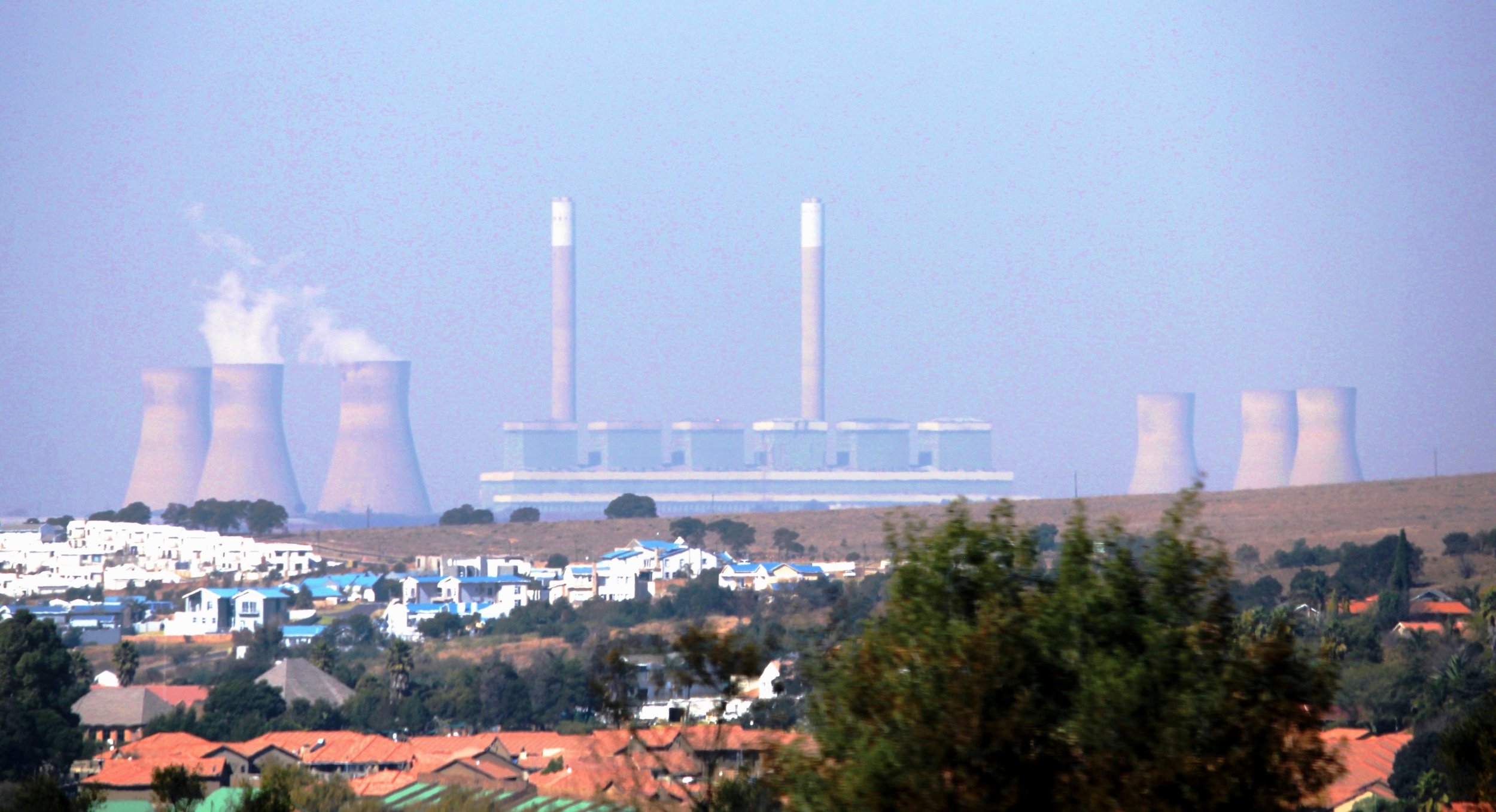 Power plant with cooling towers and smokestacks near residential houses