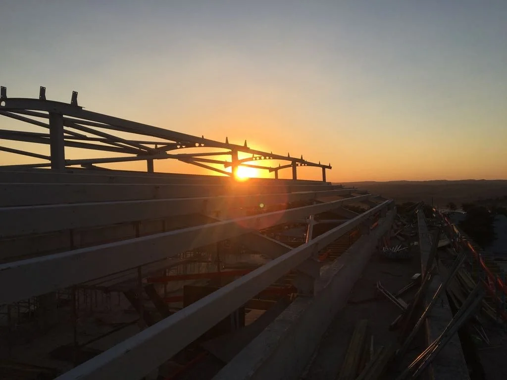 Construction site on a building with metal framing, at sunset with a clear sky.
