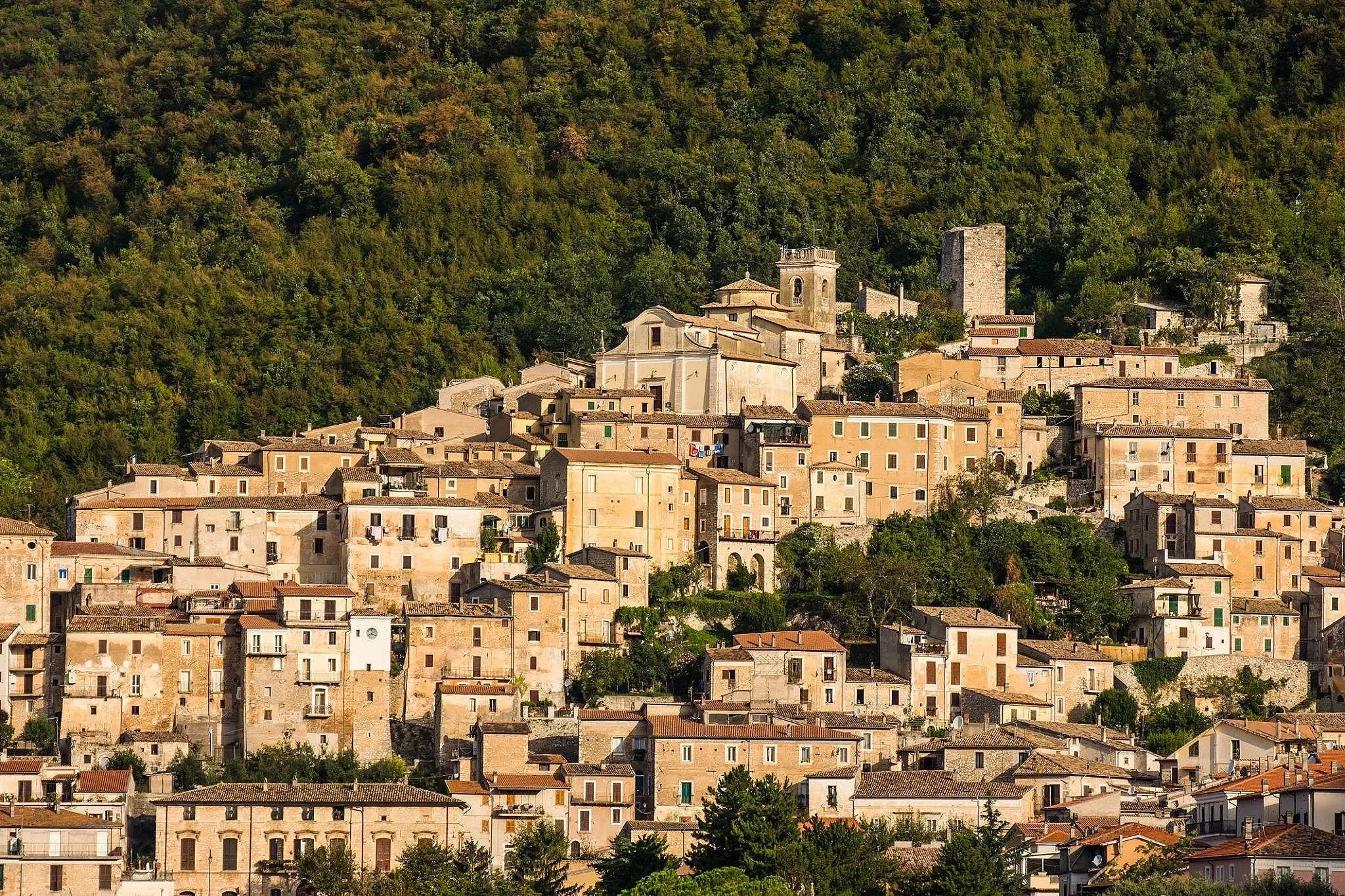 San Donato Val di Comino, a medieval Italian hill town with stone buildings clustered above the wooded slopes of the Comino Valley.