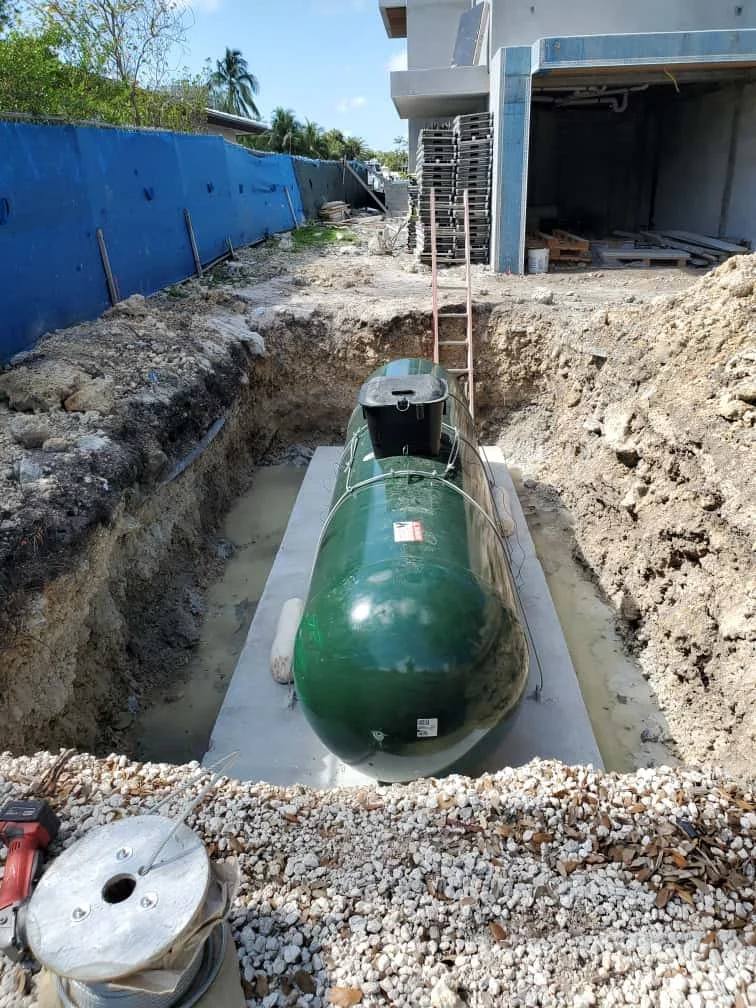 Underground tank being installed in a construction site, with digging and construction materials around.