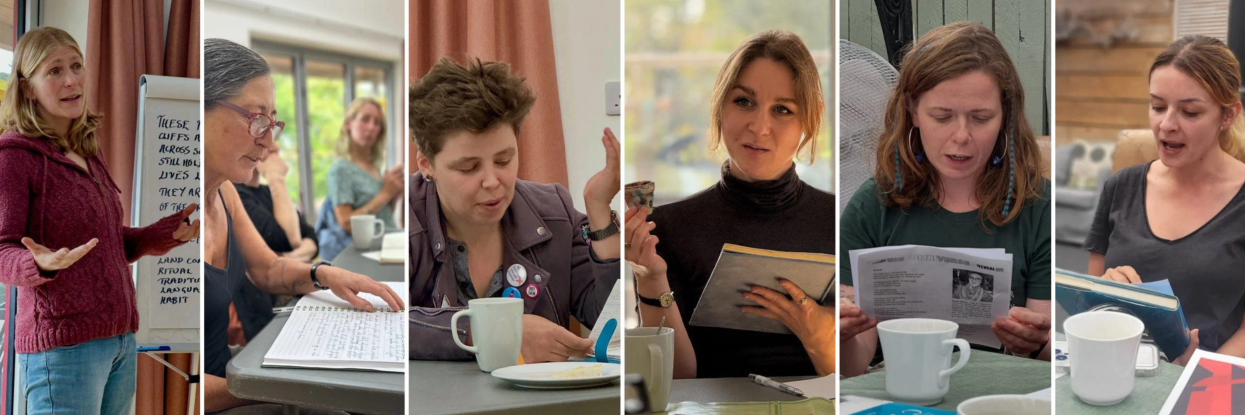 Six women engaged in a discussion or meeting; one woman is standing and speaking, others are seated reading or taking notes at a table with coffee mugs.