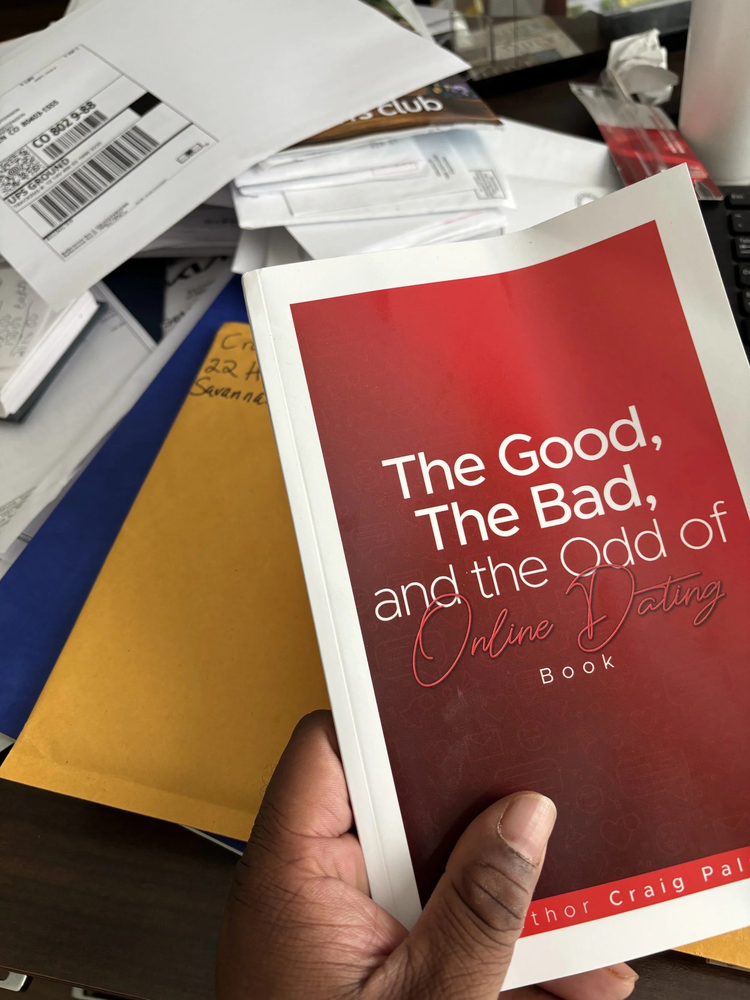 A person holding a book titled 'The Good, The Bad, and the Odd of Online Dating' by Thor Craig Palk.