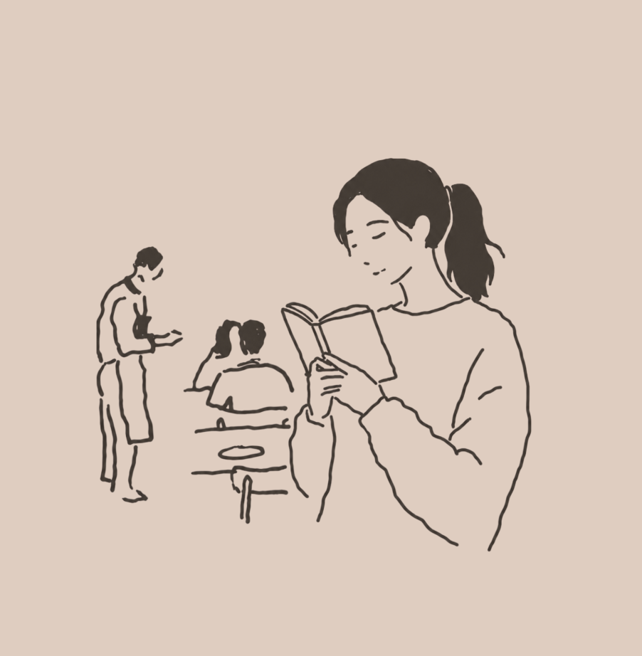 A woman reading a book at a table in a café, with other people in the background.