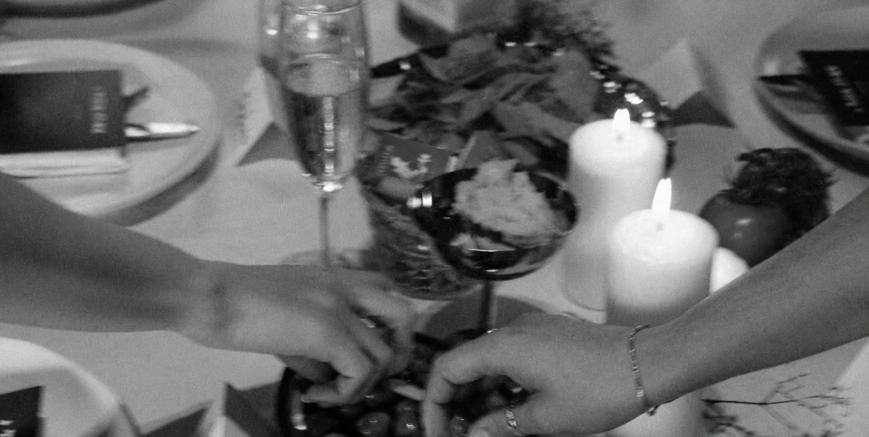 People toasting with glasses of wine at a celebration dinner with candles, food, and decorations on the table.