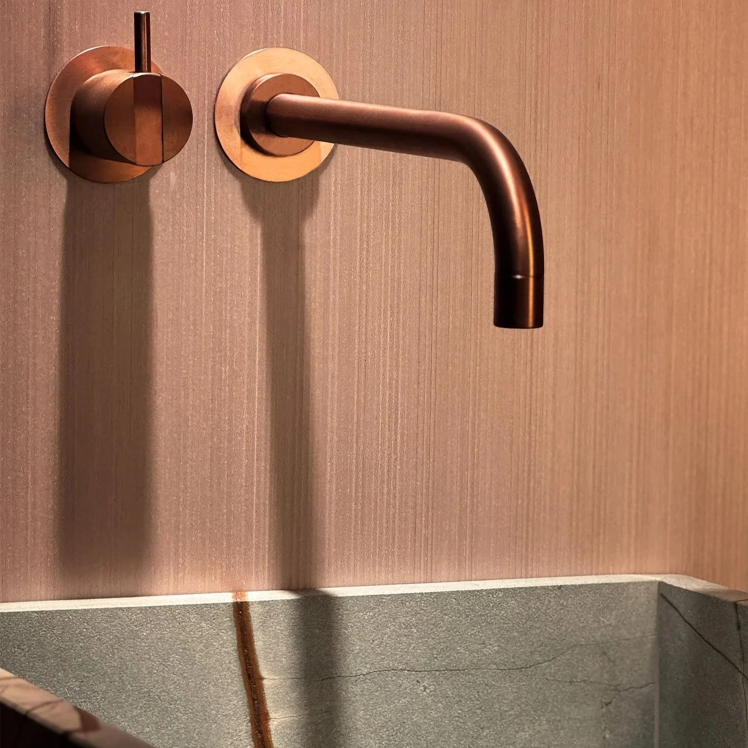 Ein moderner Wasserhahn an einer Wand, mit Ablage darunter.