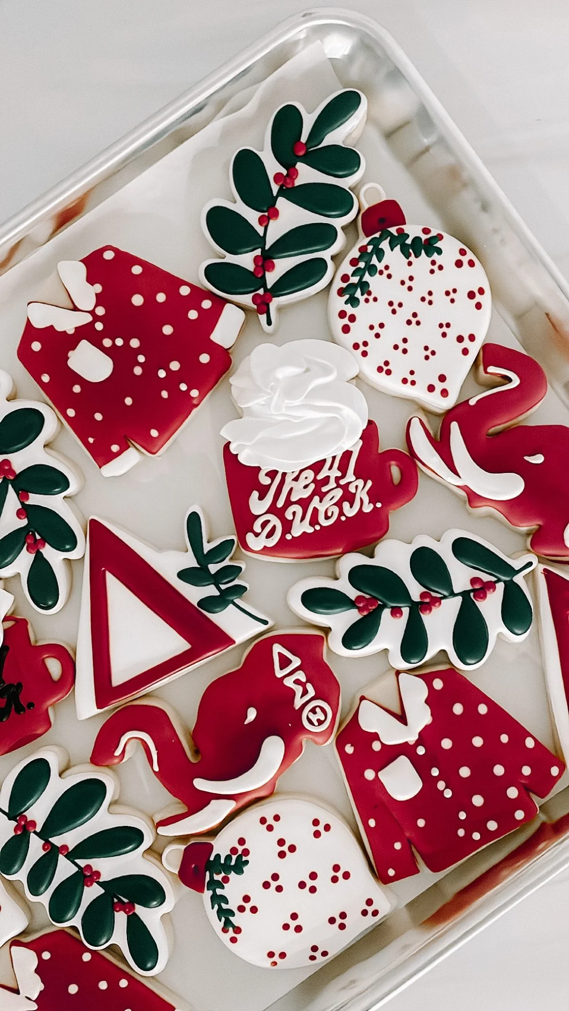 Close-up of holiday-themed iced cookies in red, white, and green with Christmas designs and text.