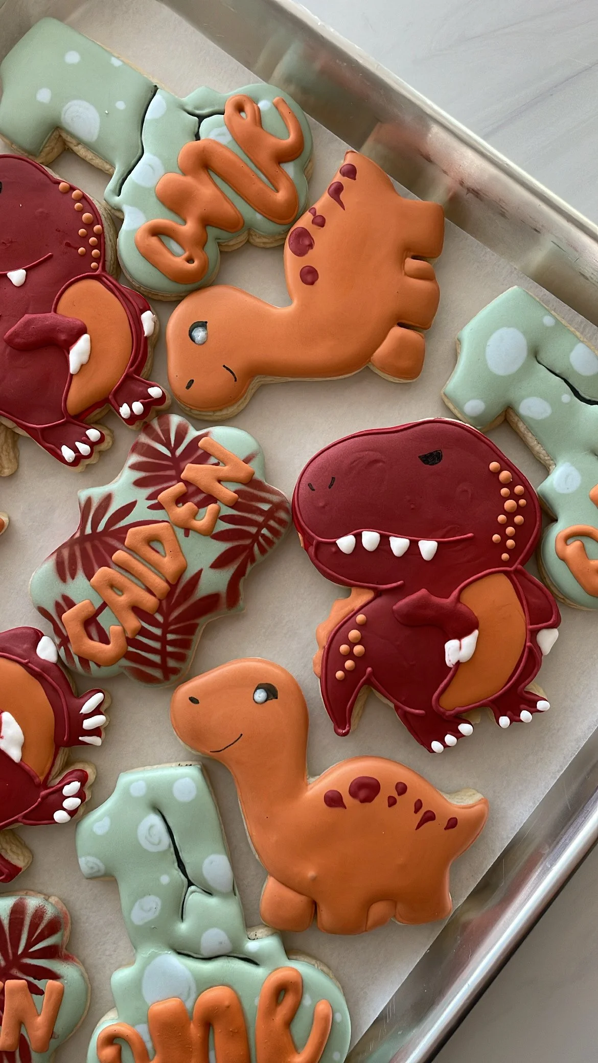 Various decorated cookies in Halloween theme, including dinosaurs and the word "BOO" with festive icing.