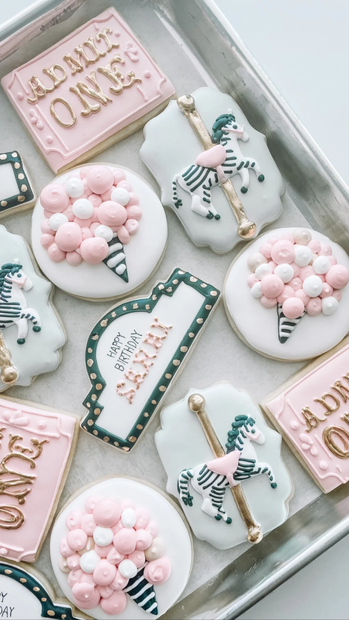 Decorated birthday cookies with a pastel color theme, including a rectangular cookie with the words 'Birthday Queen' in gold icing, round cookies with pink and white balloons, a rectangular cookie with a birthday message, and unicorn-themed cookies w