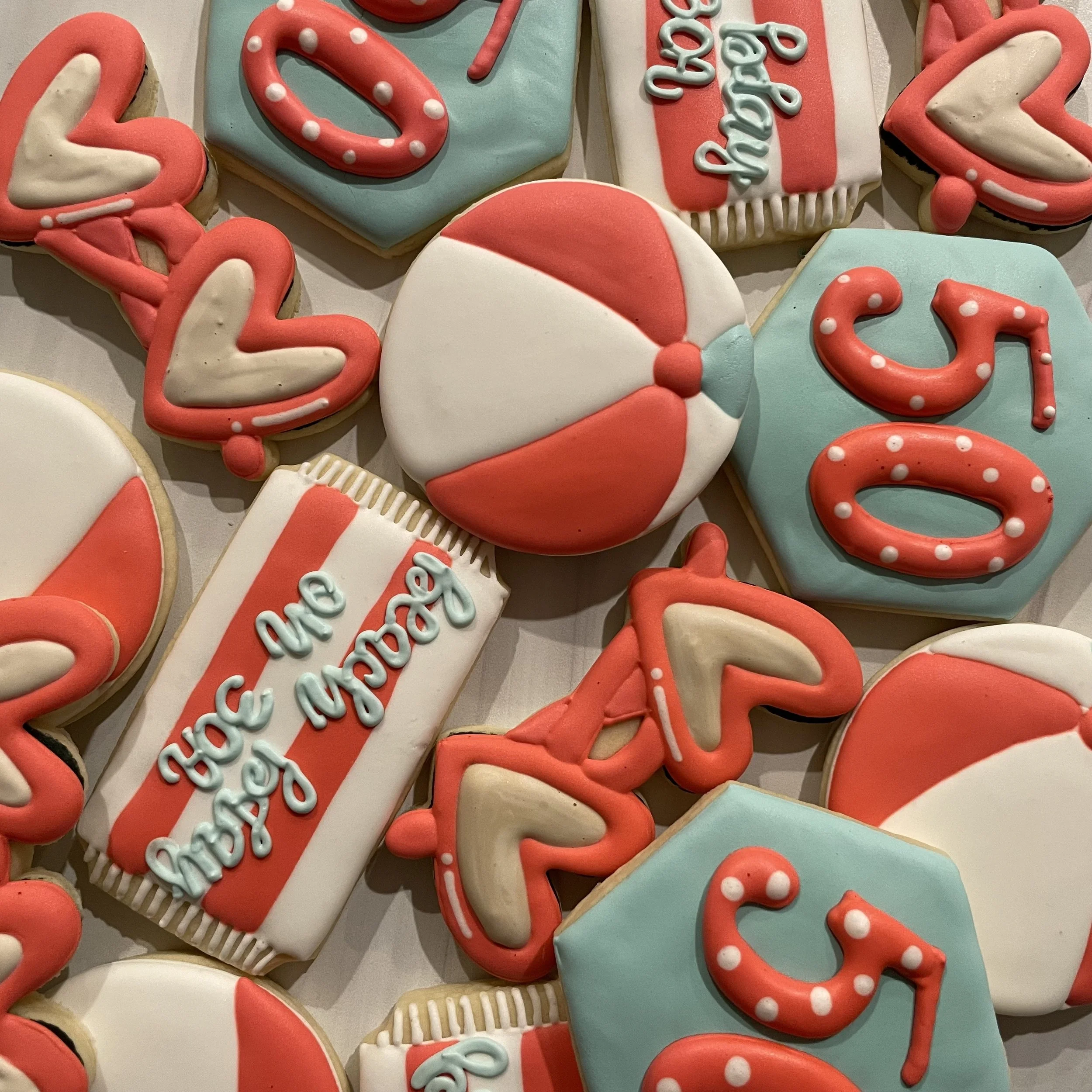 Decorated cookies with Christmas theme, including the words 'We Love You', a candy cane, a Santa hat, and various other holiday-themed shapes in red, white, and light blue icing.