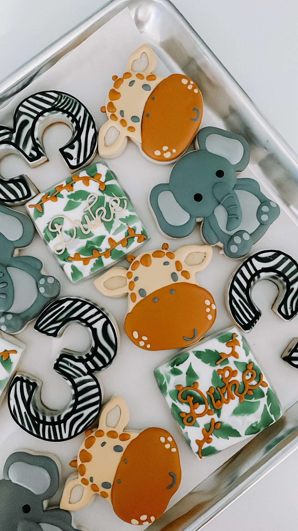 Decorated sugar cookies with animal and question mark shapes, and a cake with green leaves and the word "Dure" in white script.