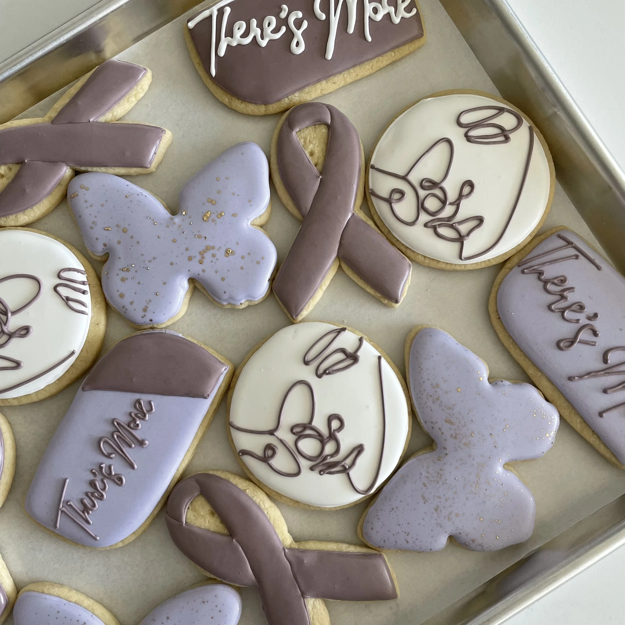 Decorated cookies on a tray, some with icing and writing, others with heart or arrow shapes for Valentine's Day.