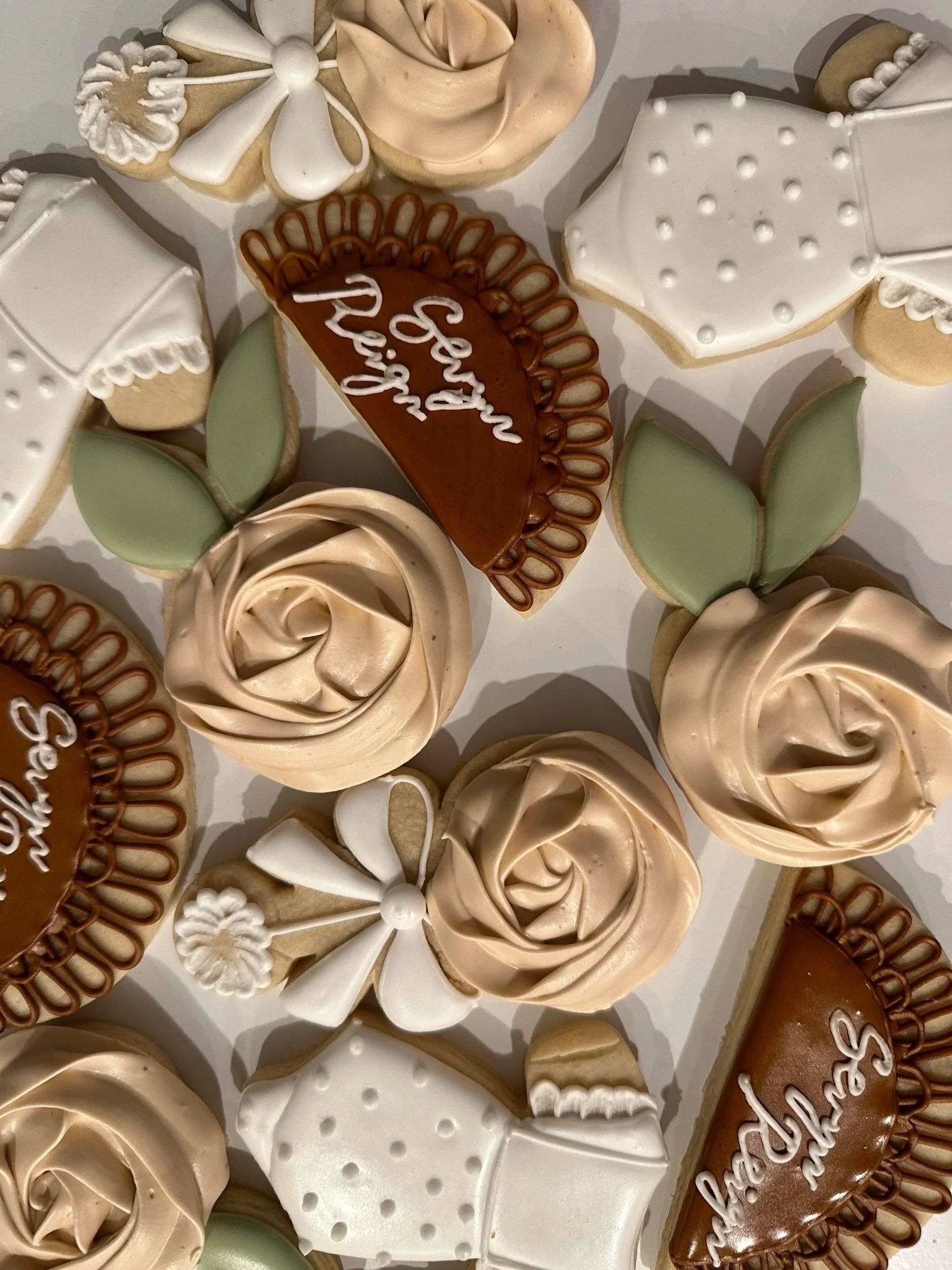 Various decorated cookies, including roses, leaves, and heart-shaped cookies with icing, arranged on a surface.