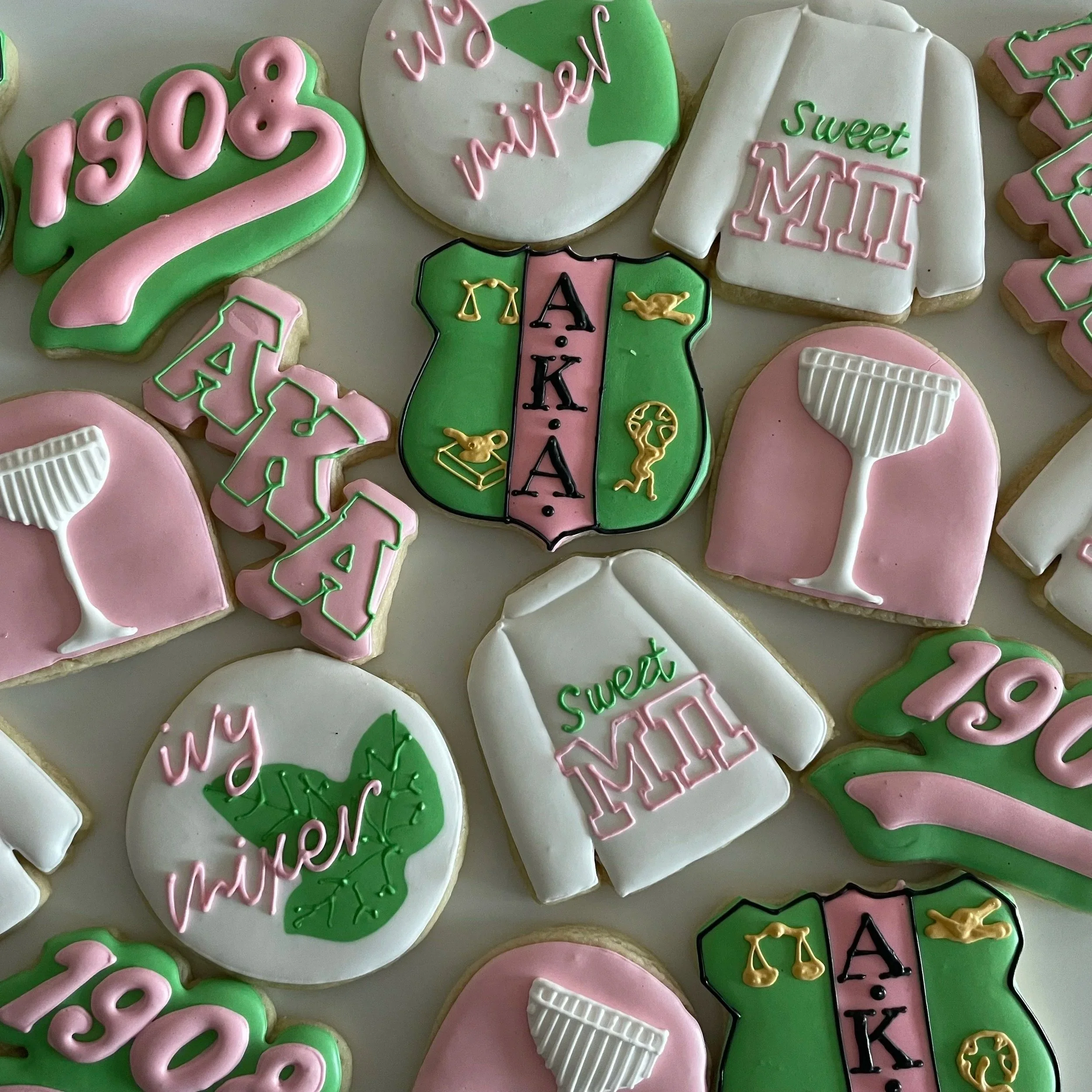 Decorated cookies celebrating an academic achievement, featuring the number '2023', a graduation cap, and a school emblem with scales of justice and a gavel, all in pastel pink, green, white, and black icing.
