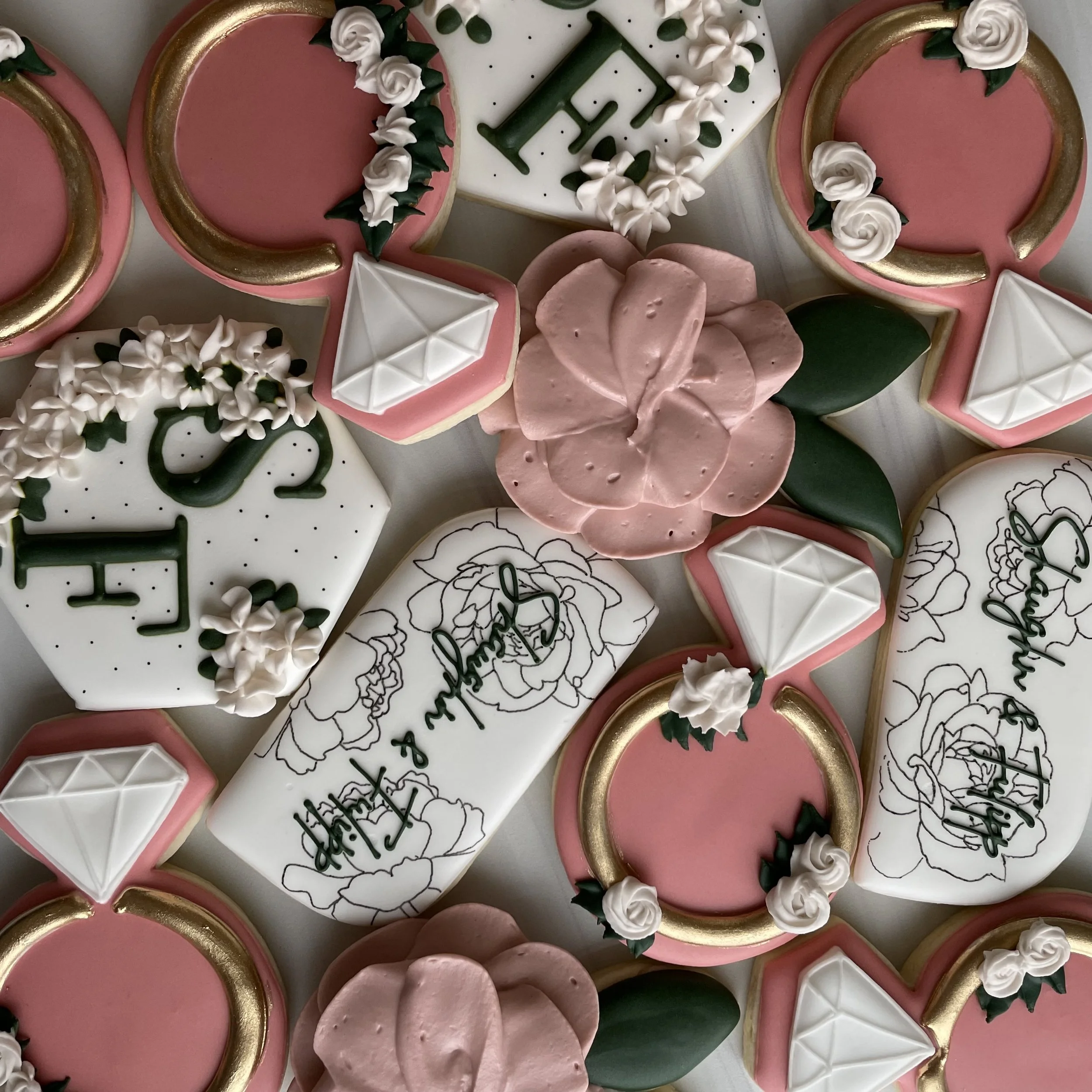 A collection of decorated cookies, including pink, white, and green themes, with floral, geometric, and holiday designs.
