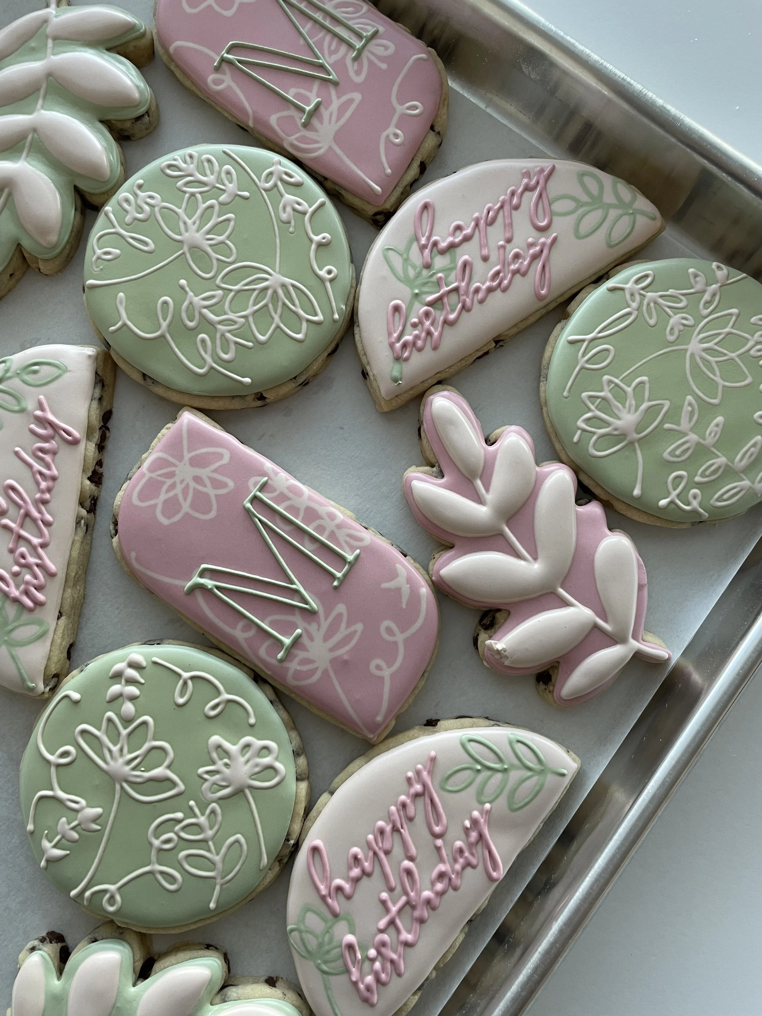 Decorated cookies for Father's Day with pastel pink, green, and white icing, featuring floral patterns, messages, and symbolic designs.