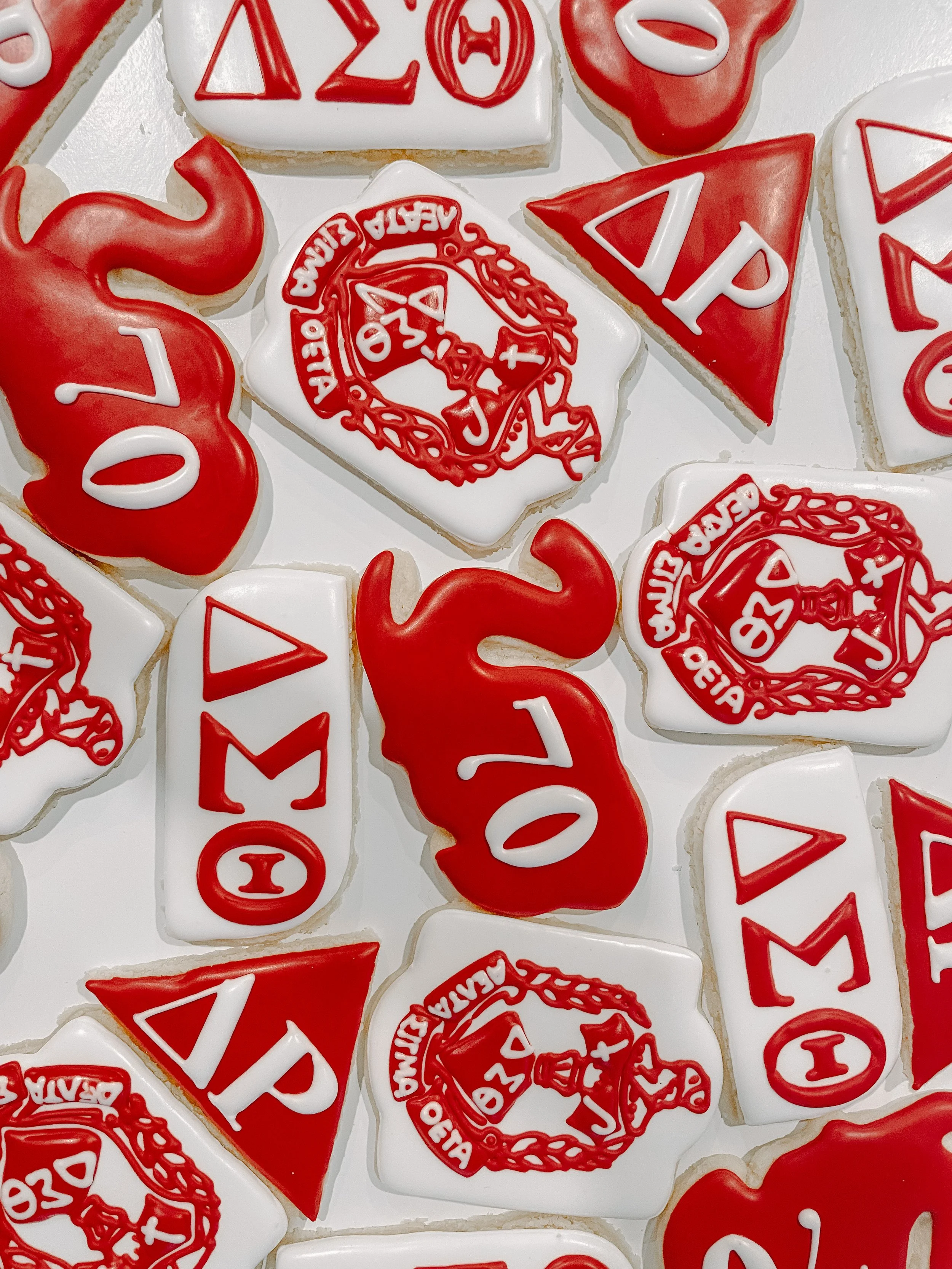 Decorated sugar cookies for graduation with red, white, and black icing, featuring the word 'GRAD' and the Greek letters "ΦΒΚ".