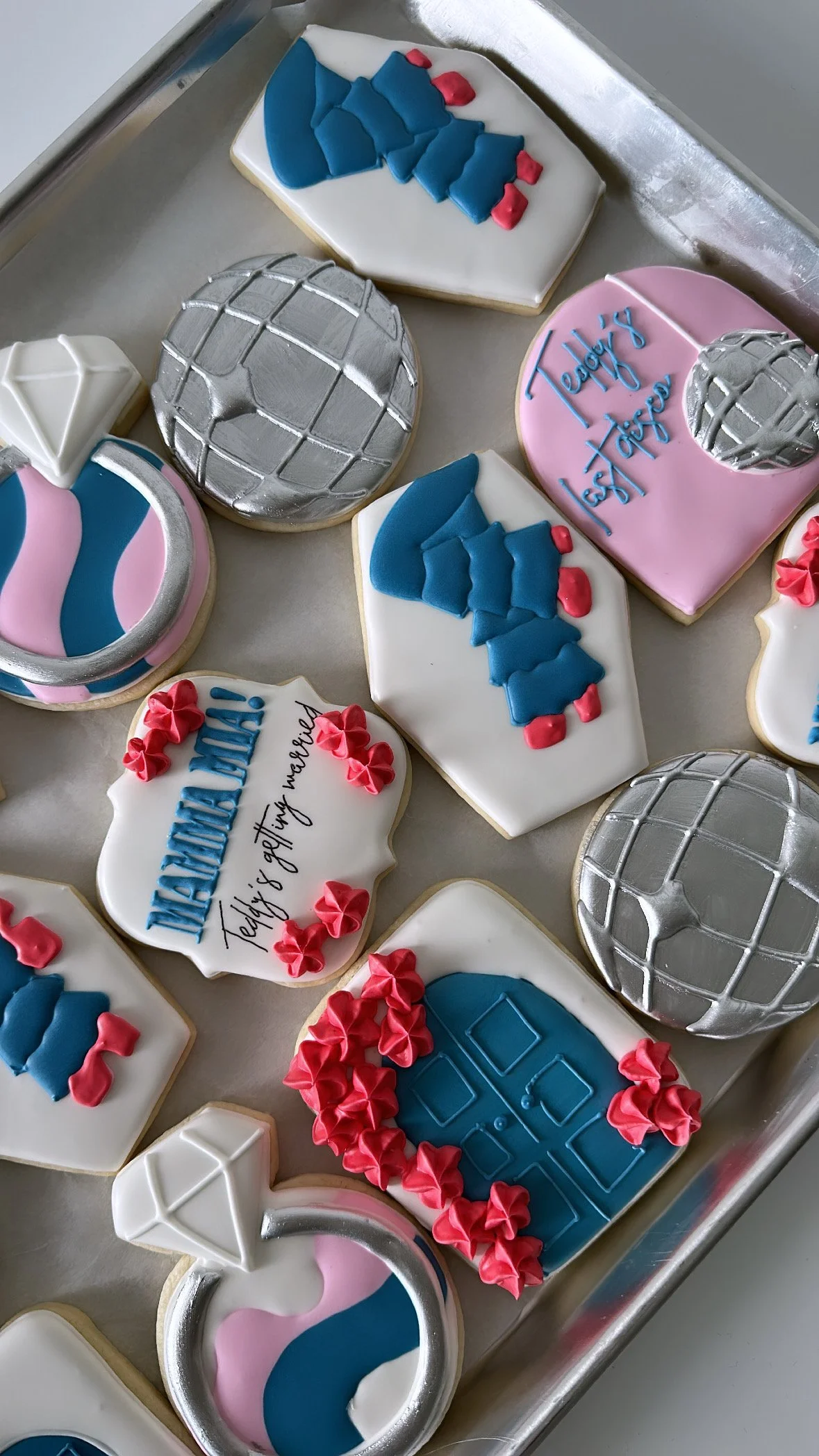 Decorated cookies with space-themed designs, including planets, a rocket, and a spaceship, on a silver tray.
