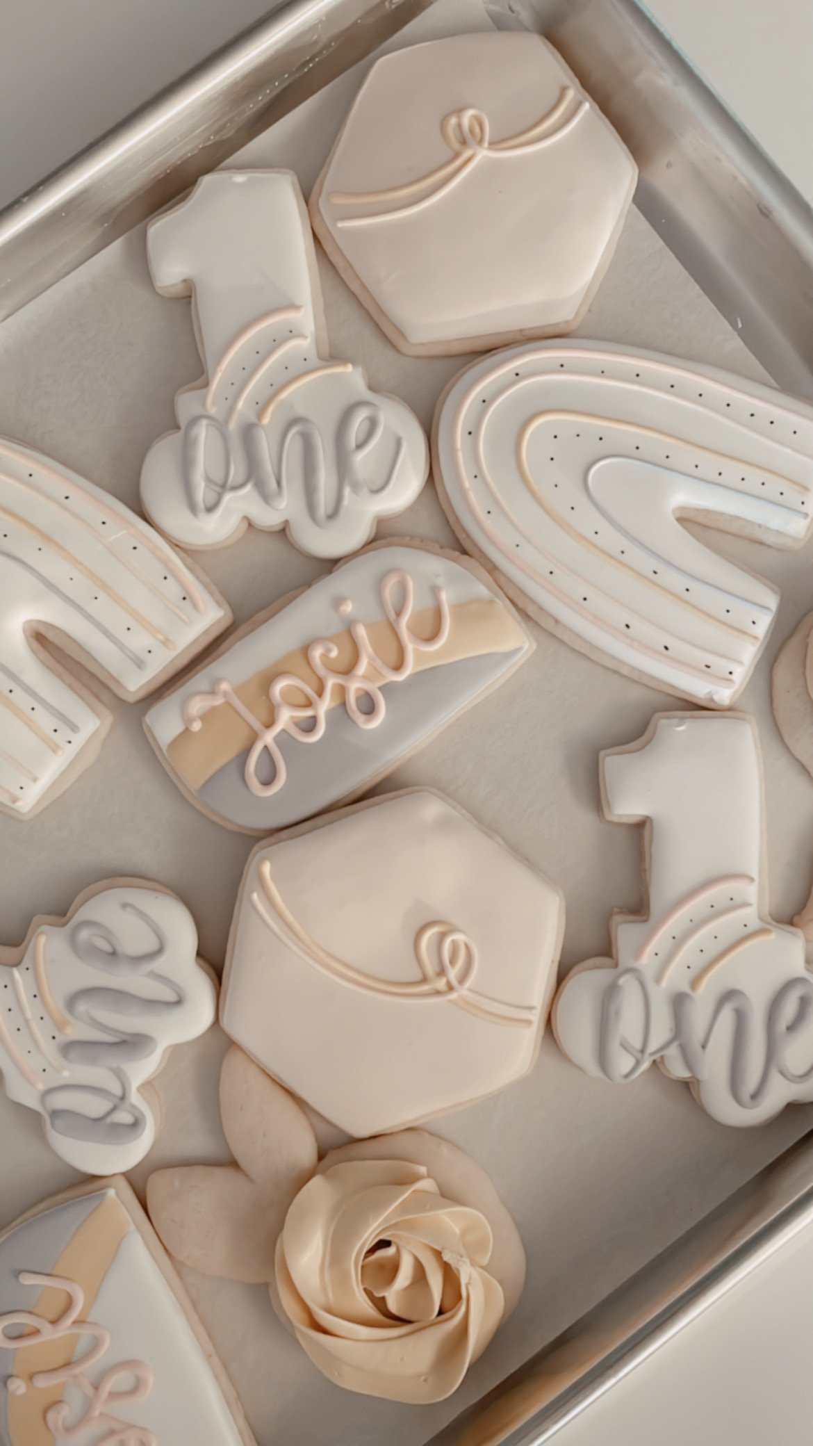 Decorated cookies with messages like 'love' and 'hope,' along with rainbows and flower shapes, all with white and light pastel icing.