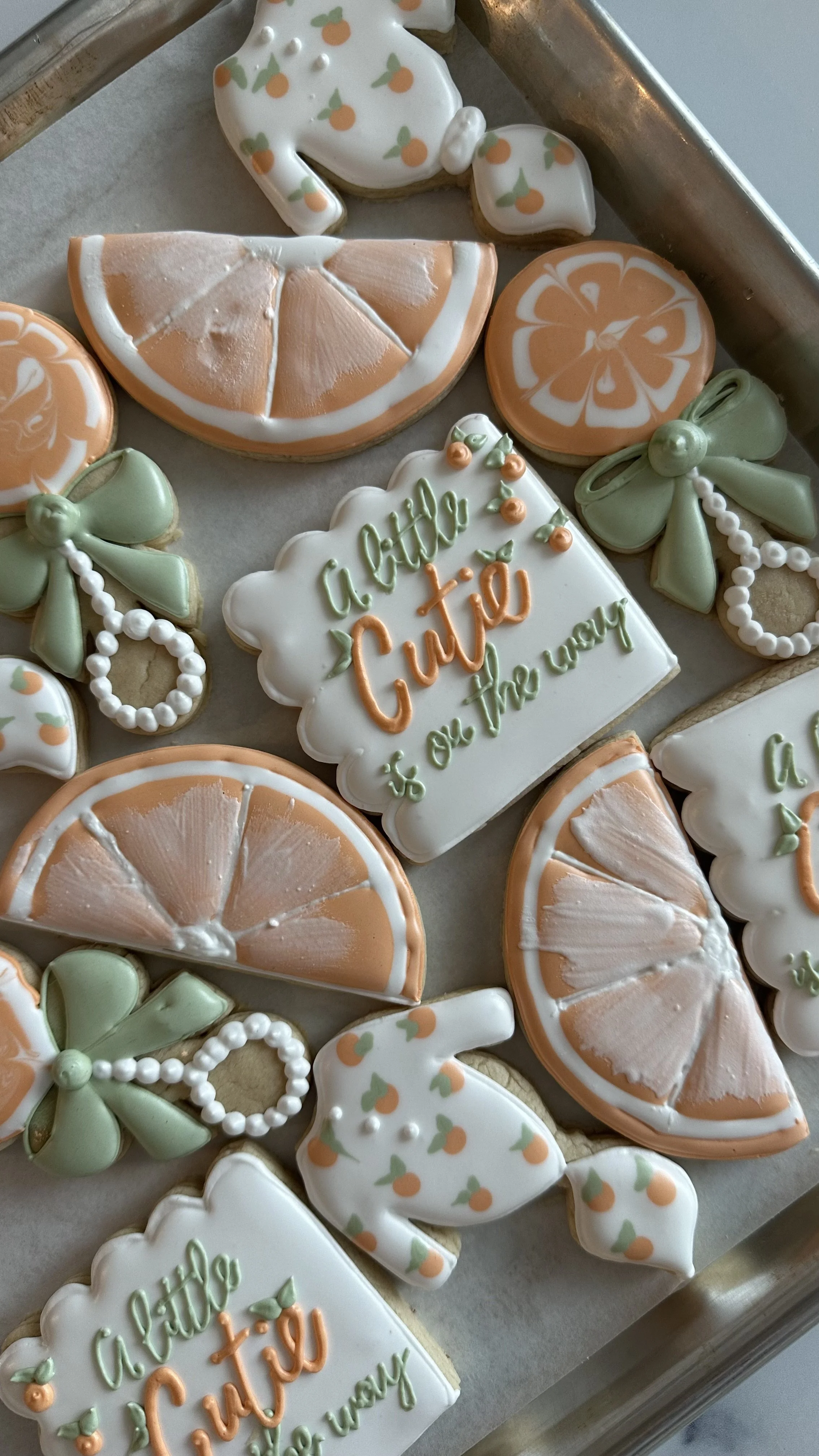 Assorted cookies decorated with orange slices, bows, and messages celebrating a citrus-themed event.