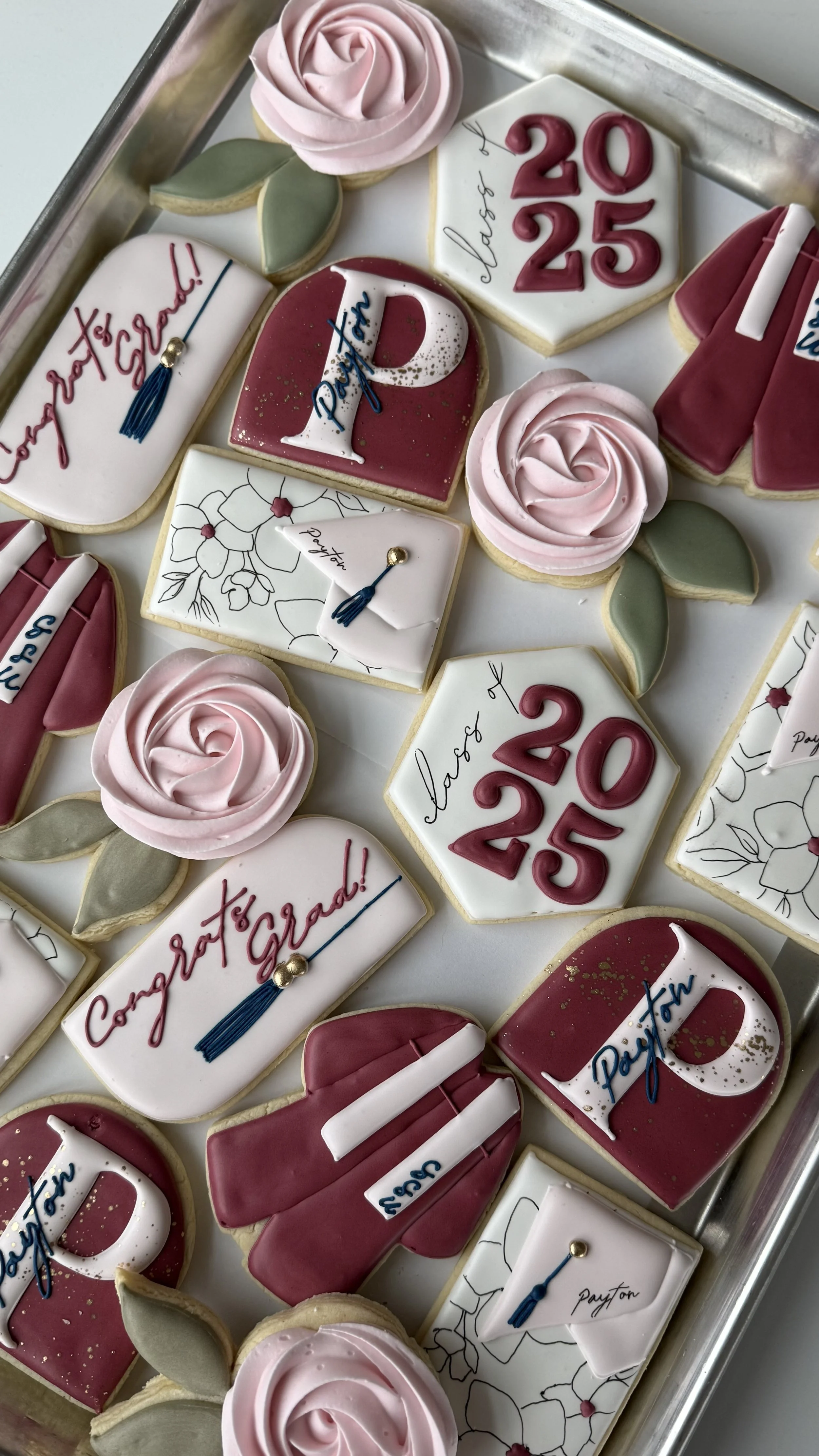 Decorated cookies celebrating graduation, featuring flowers, graduation caps, and the year 2025.