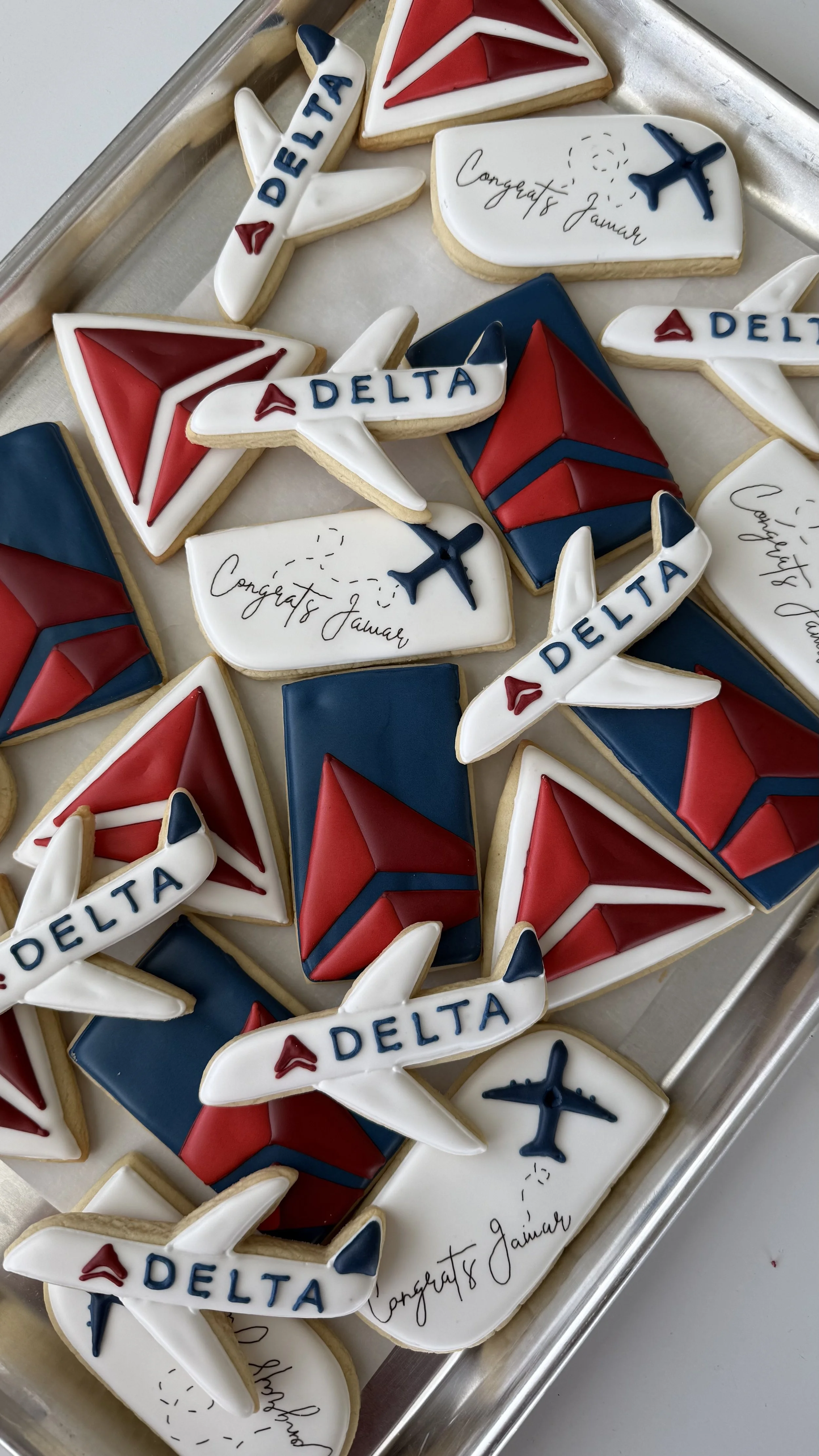 Decorated cookies with airline and travel themes, featuring Delta Air Lines logos, planes, and 