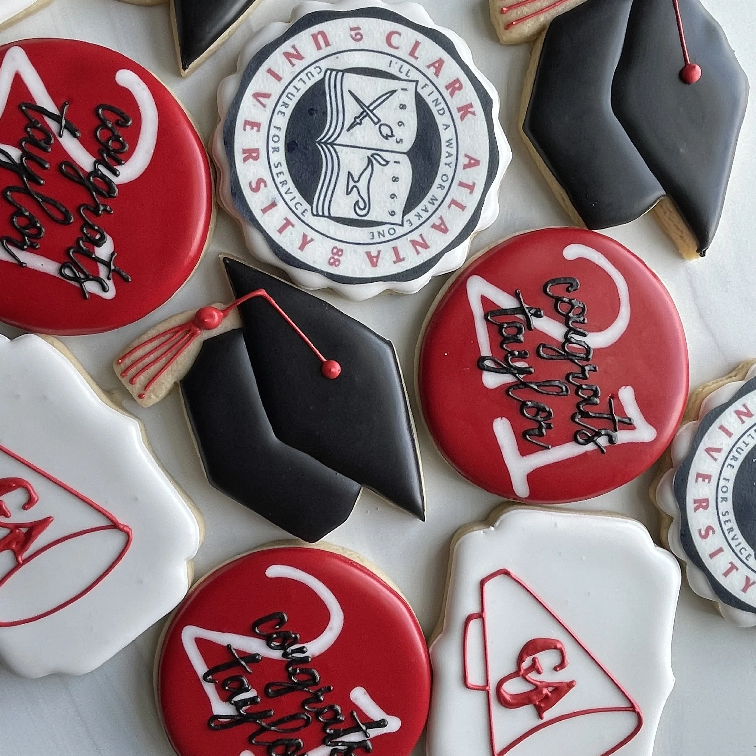 Decorated cookies with graduation and university themes, including a university crest, red and white colors, and a graduation cap shape.