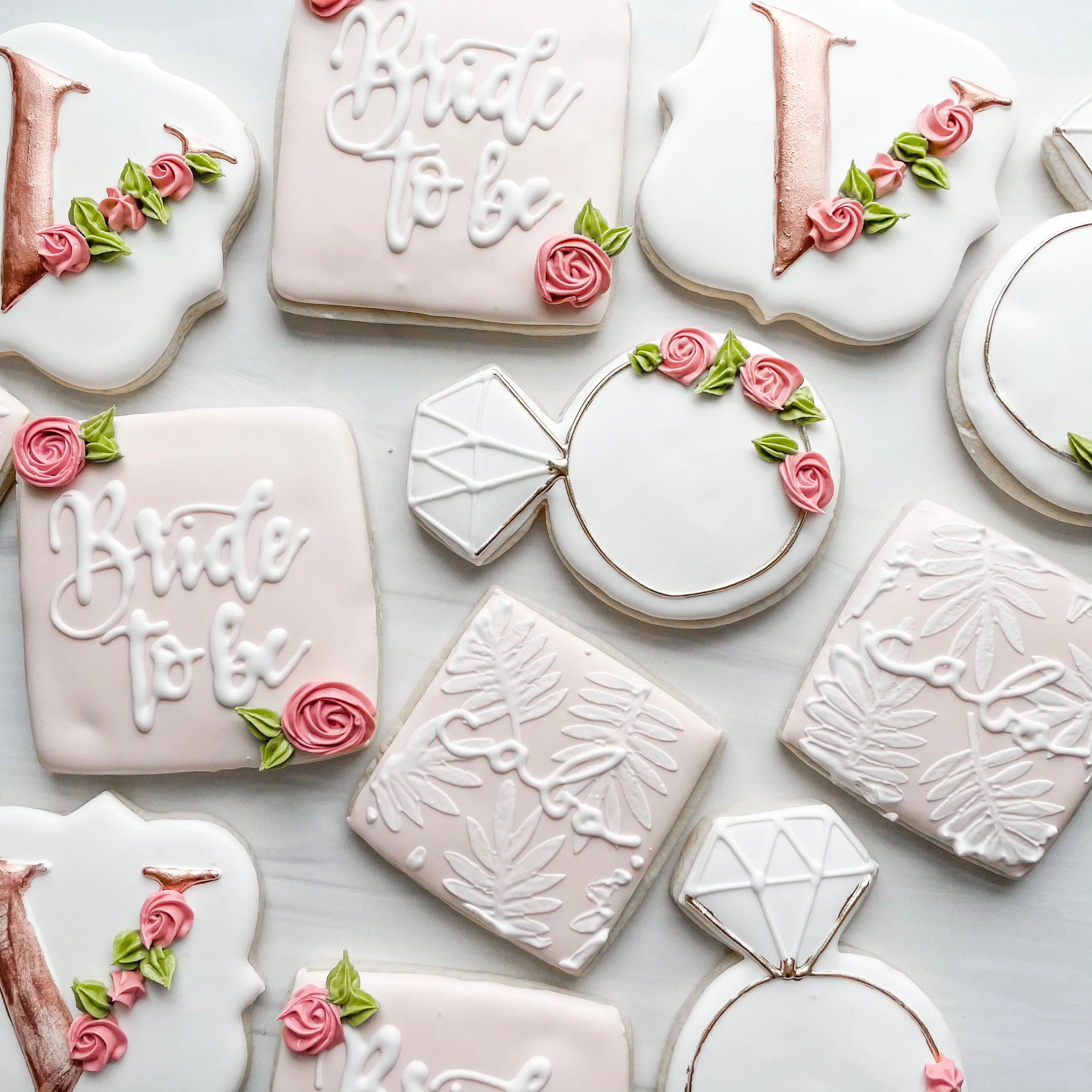 Decorative cookies with pink and green frosting, some shaped as flowers and others with messages, on a light background.