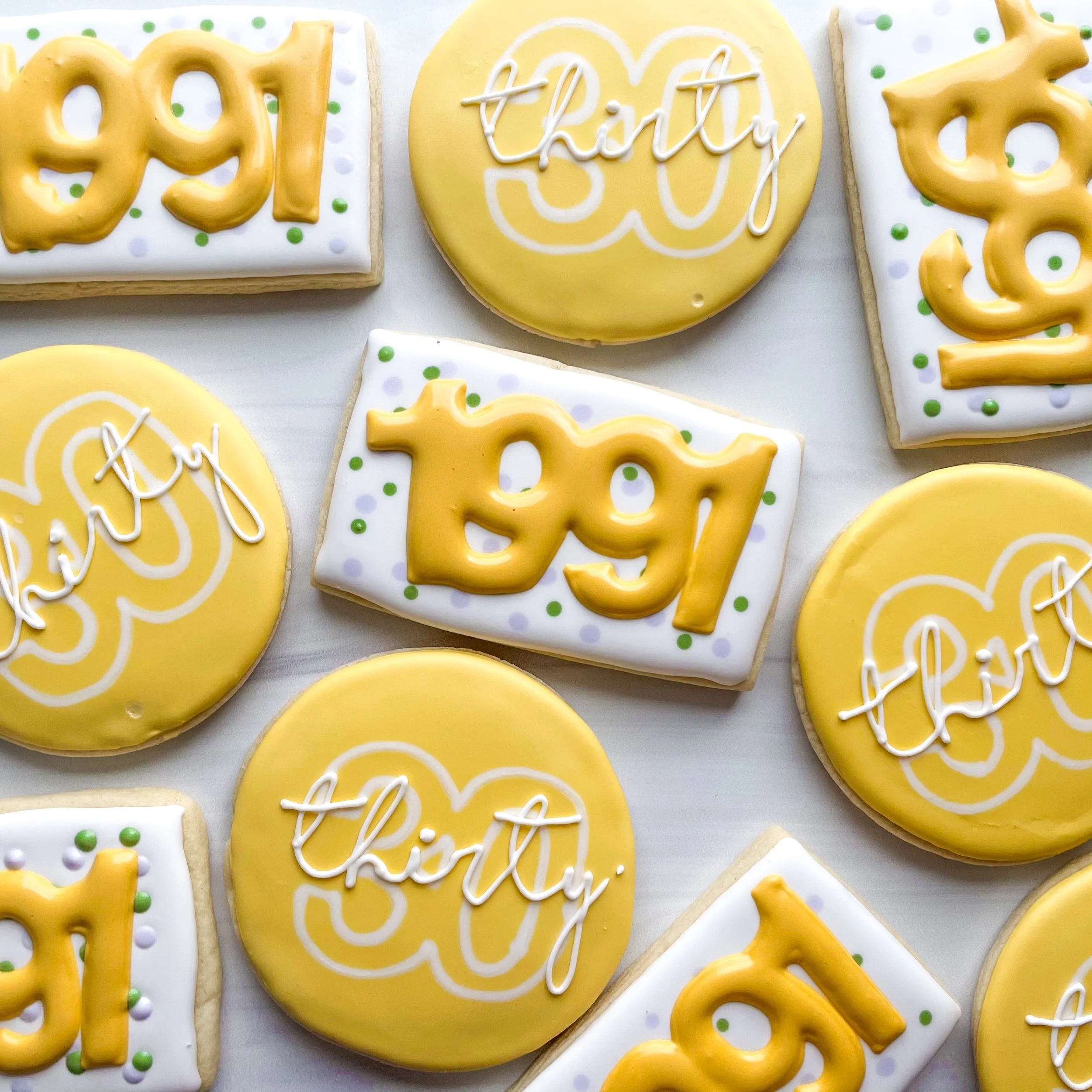Yellow cookies with white icing and yellow or white piping with the words 'Happy' and 'Birthday' written on them.