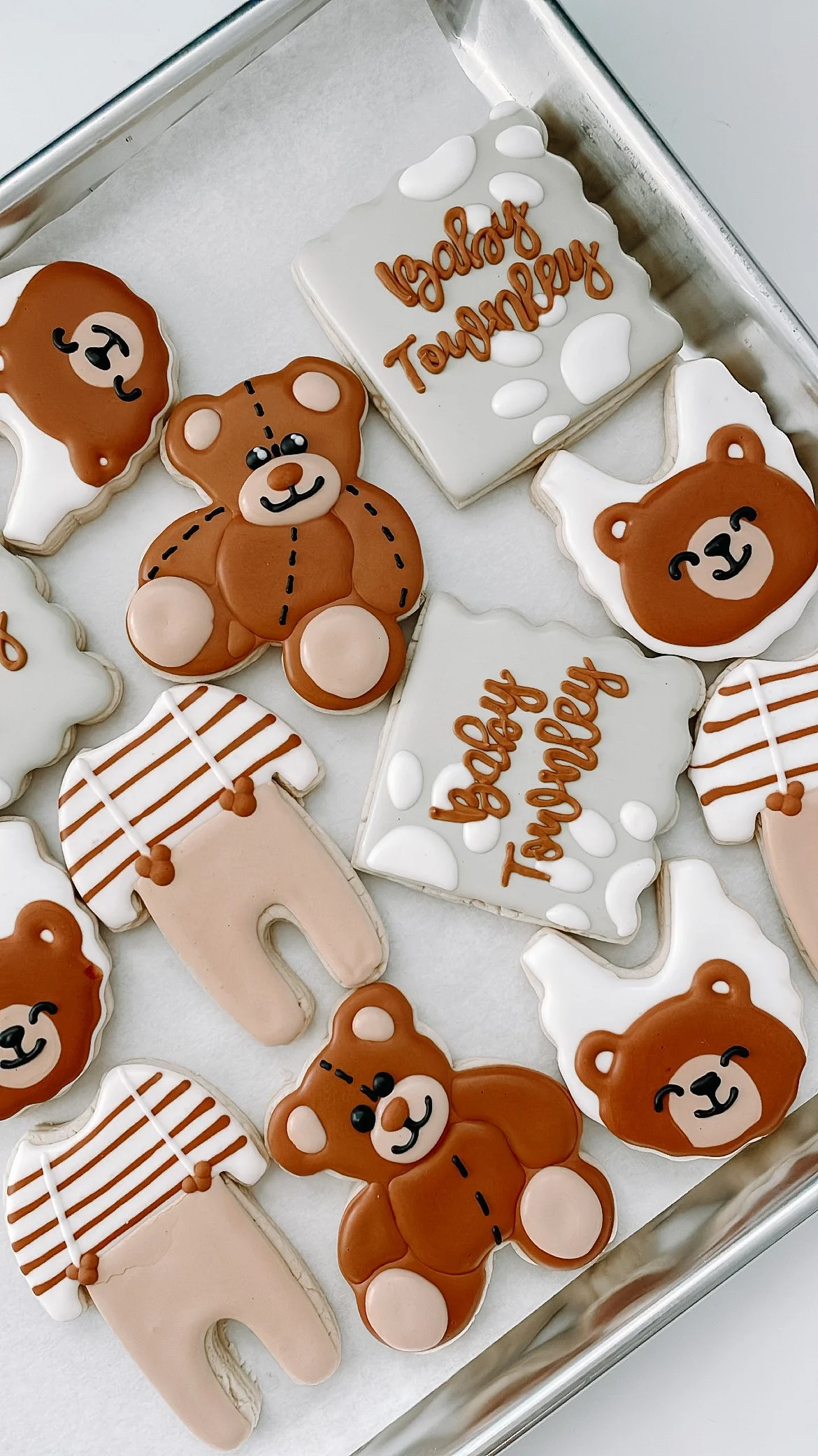Decorated cookies with teddy bears and messages for a baby shower, including phrases like "baby shower" and "baby tourney."