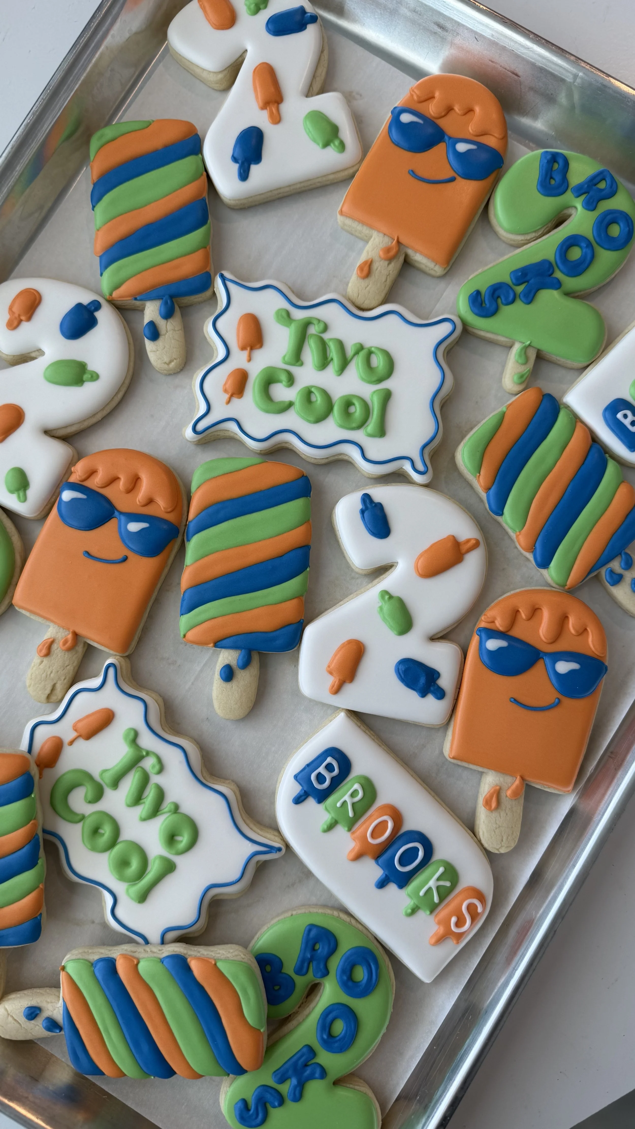 Colorful decorated cookies with summer theme, including sunglasses, popsicles, and tropical messages like "Two Cool" and "BROOKS."
