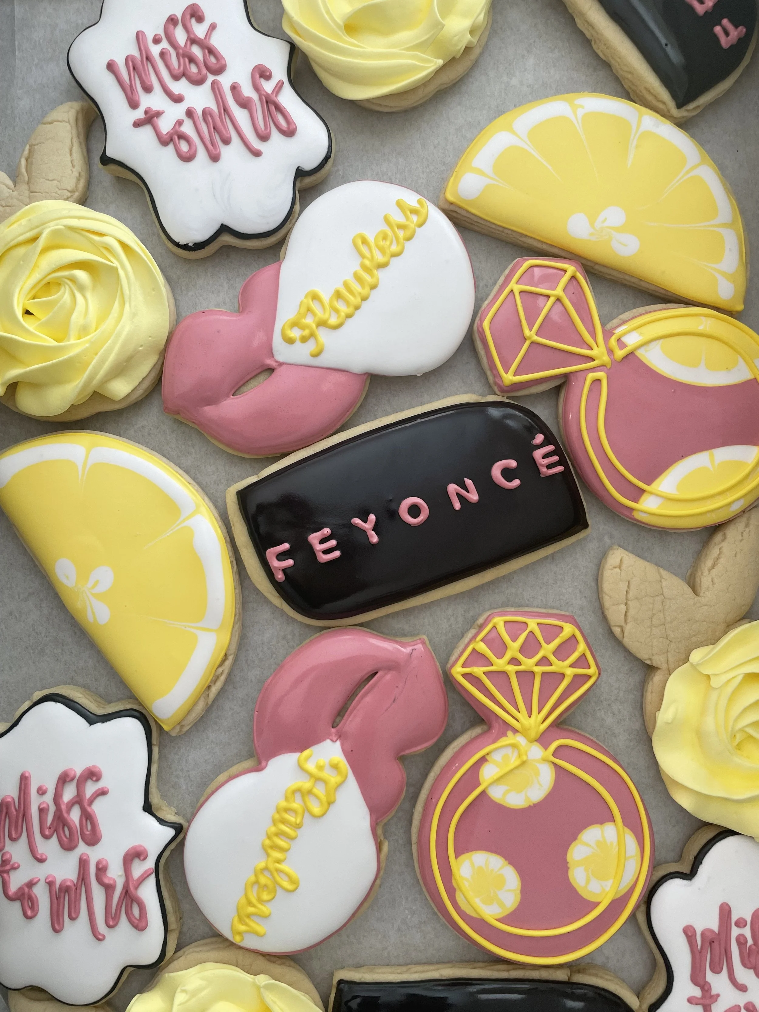 Decorative cookies with various designs and phrases including lemon slices, pink lips, and words like 'miss' and 'peace' written in colorful icing.