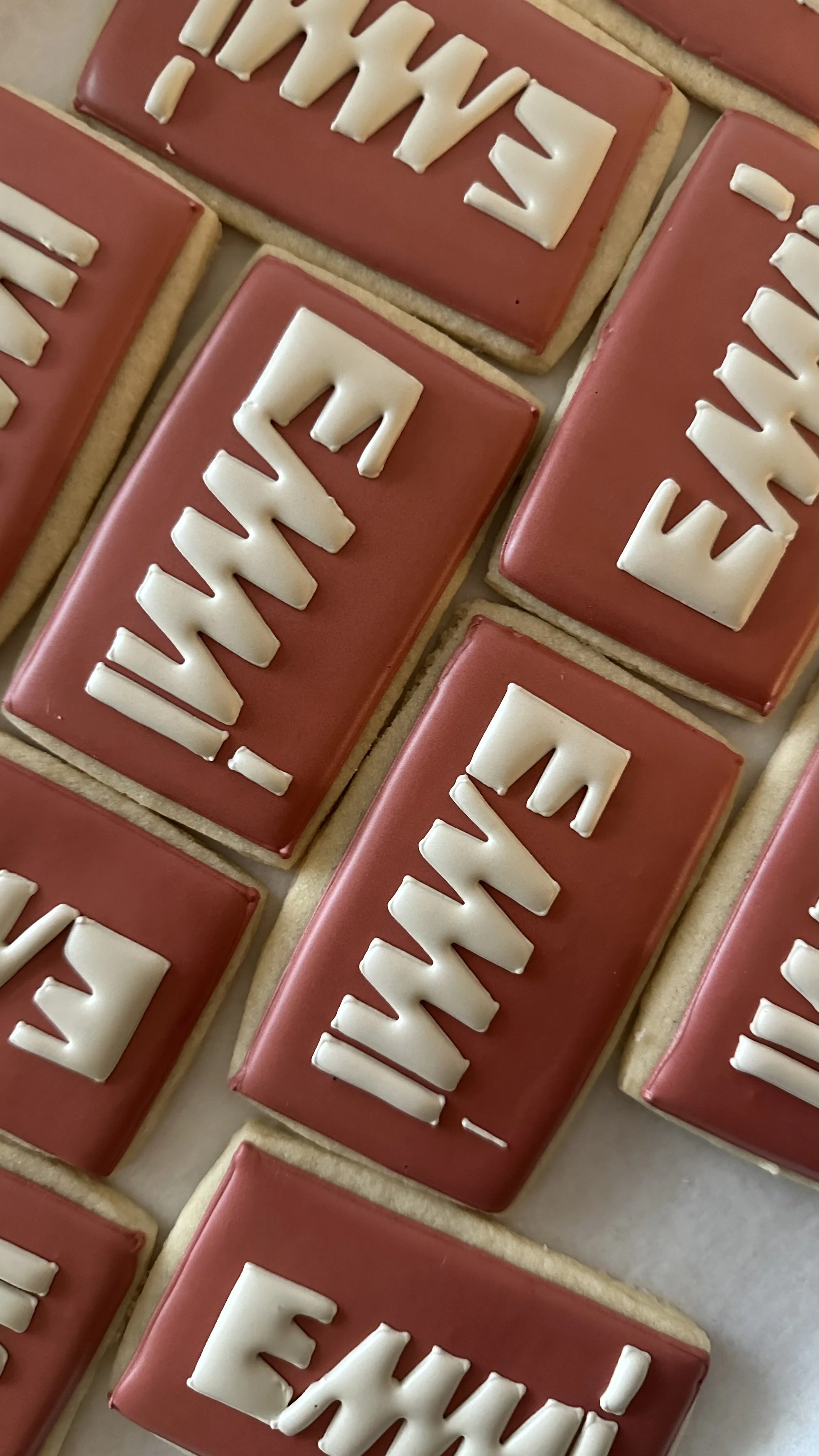 Rectangular cookies with red icing and white letter icing spelling out "Merry".