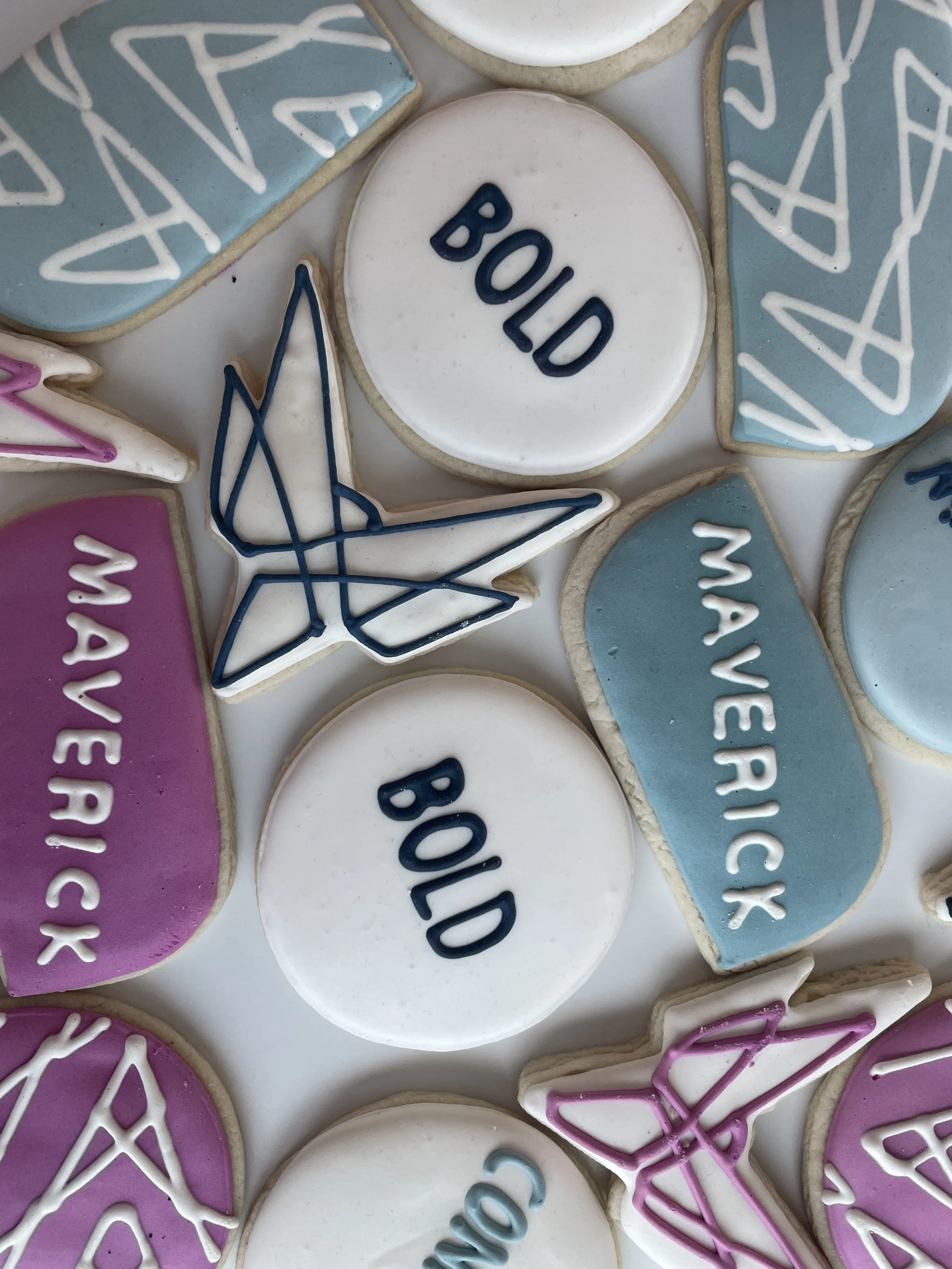 A collection of decorated cookies with messages including 'BOO!' and 'MAY THE SUGAR BE WITH YOU,' featuring pastel colors, stars, and geometric patterns.