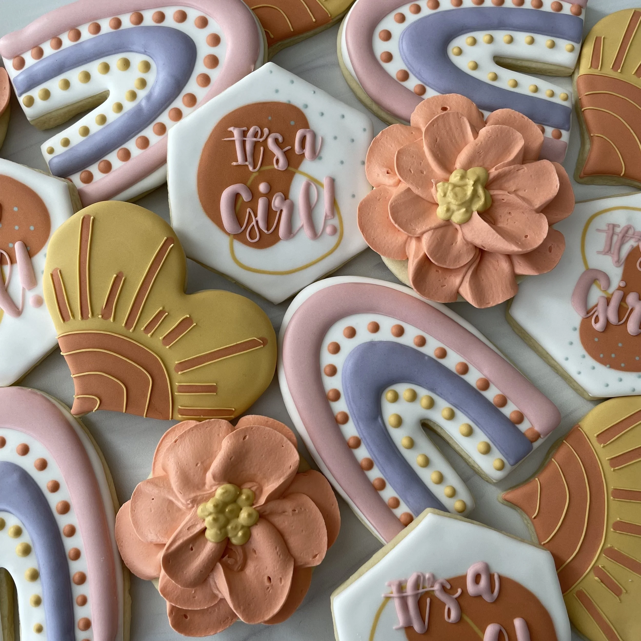 Colorful decorated cookies in pastel pink, purple, yellow, and white with floral and message designs celebrating a birthday.
