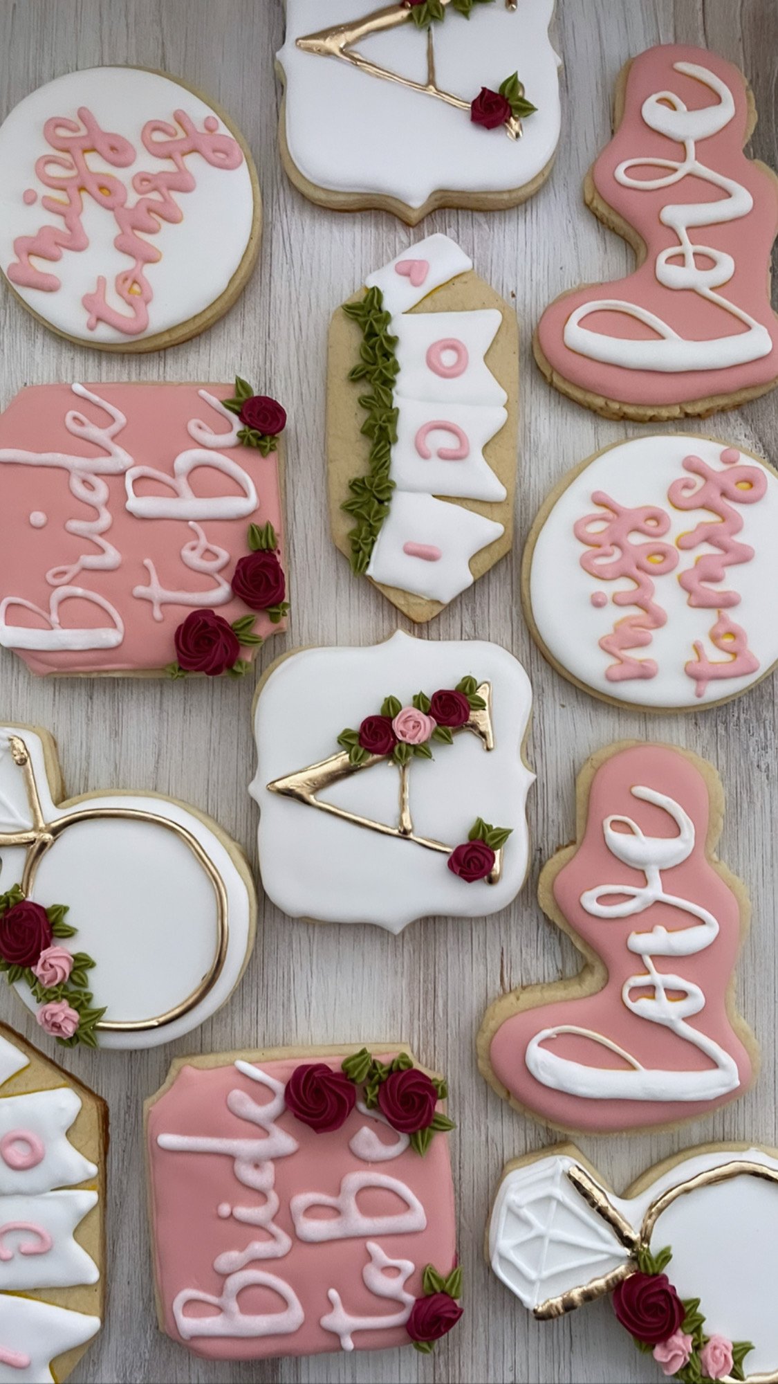 Decorated cookies with messages like "Happy Birthday" and images of bows, roses, and the word "Love" in pink, white, and gold colors.