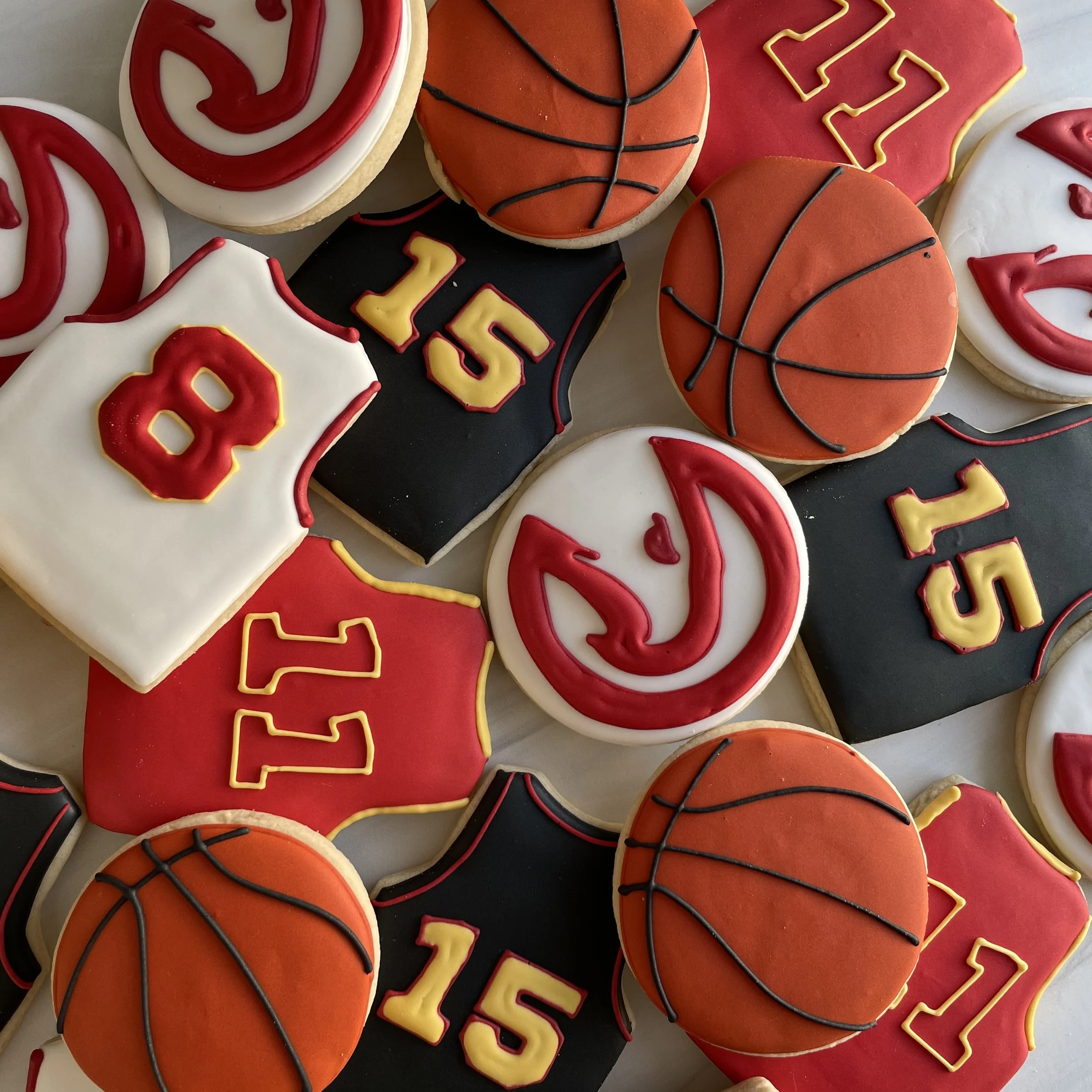 Various decorated cookies with sports themes, including basketballs and footballs, decorated with colorful icing and piping.