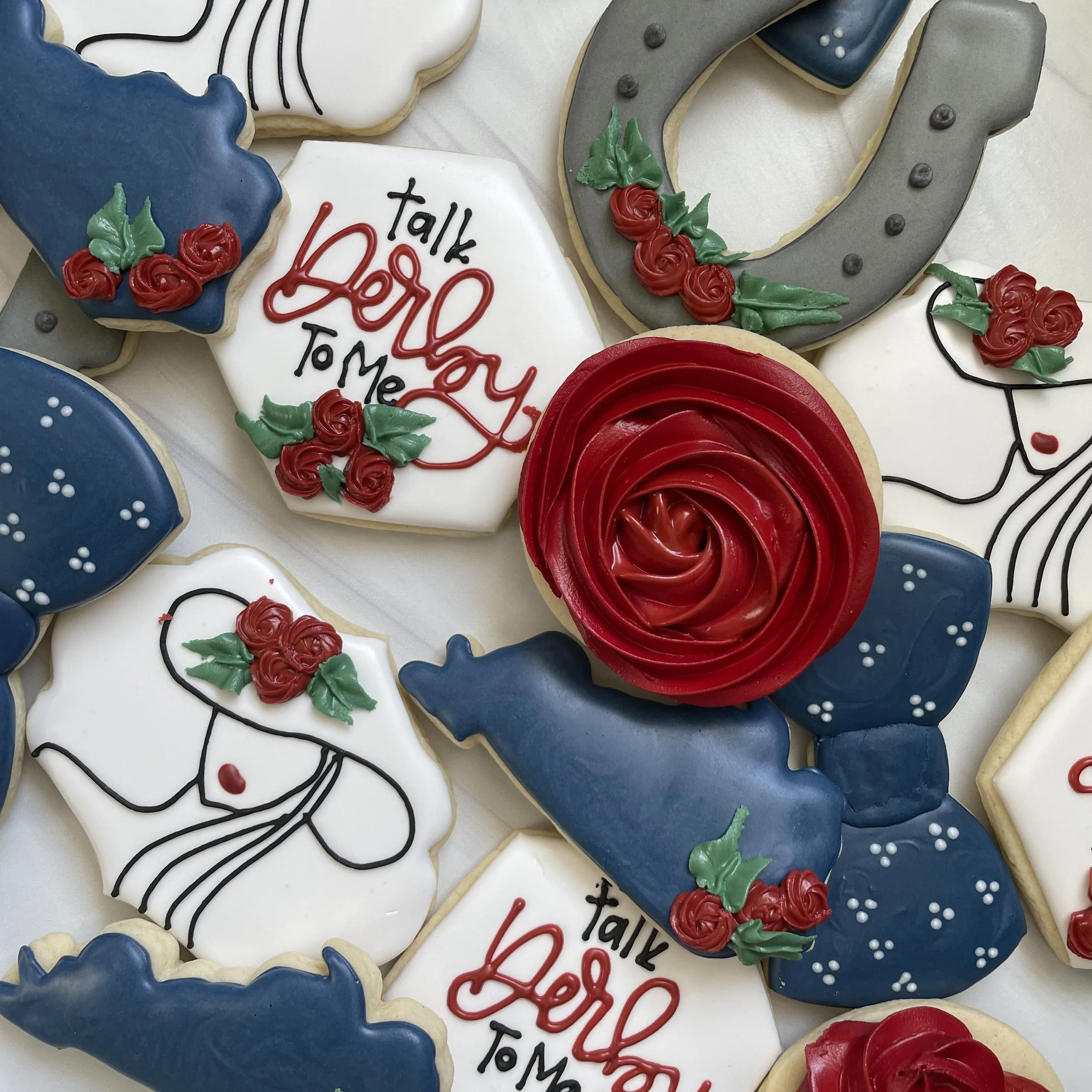 Decorated cookies with Christmas theme, including a white cookie with red and black writing that says "Talk to my Hand" and other cookies with holly and roses decorations.