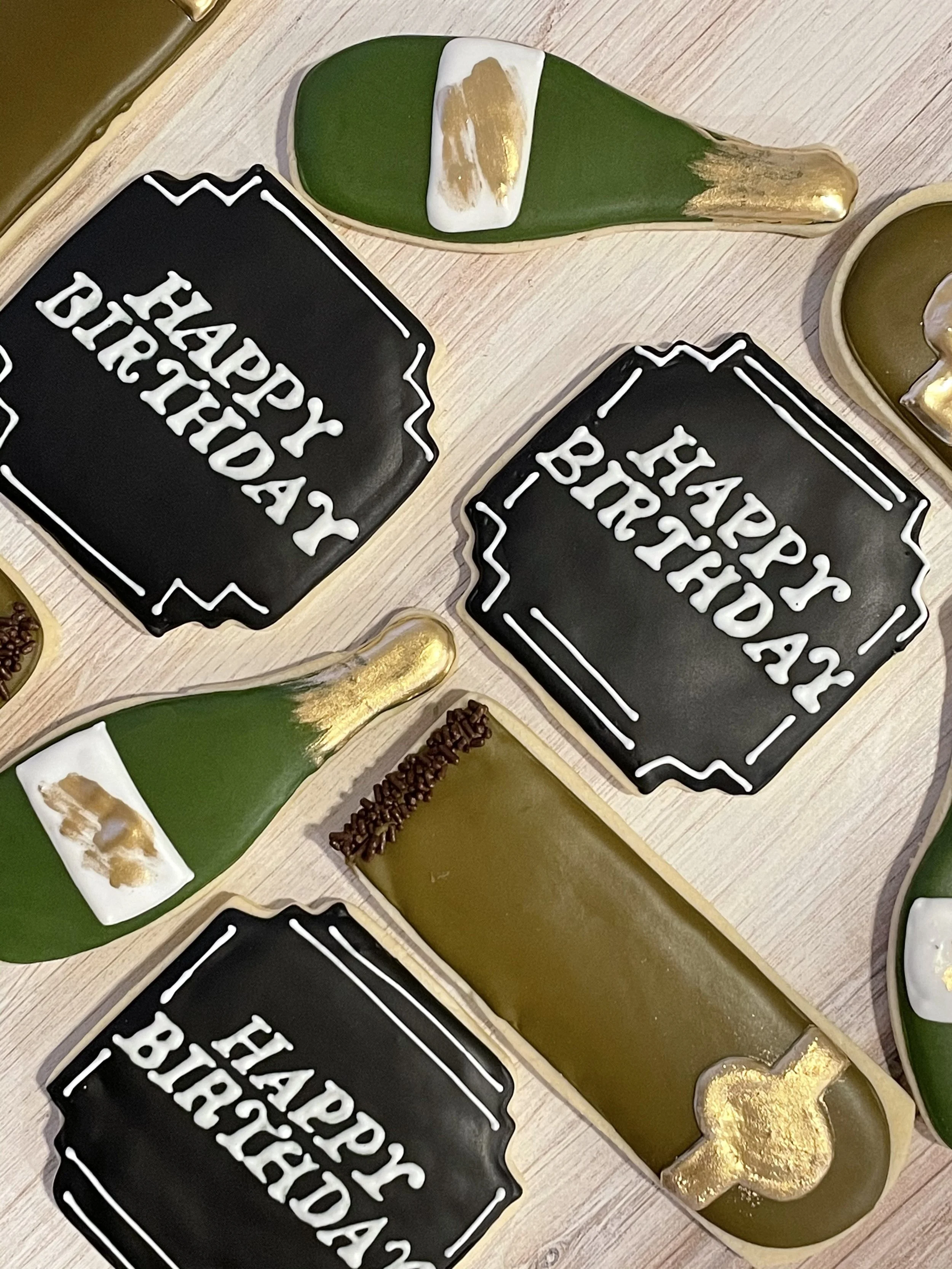 Decorative plates with birthday message, a green and gold edible decoration shaped like a shoe with gold accents, and small gold and chocolate sprinkles on a light wooden surface.