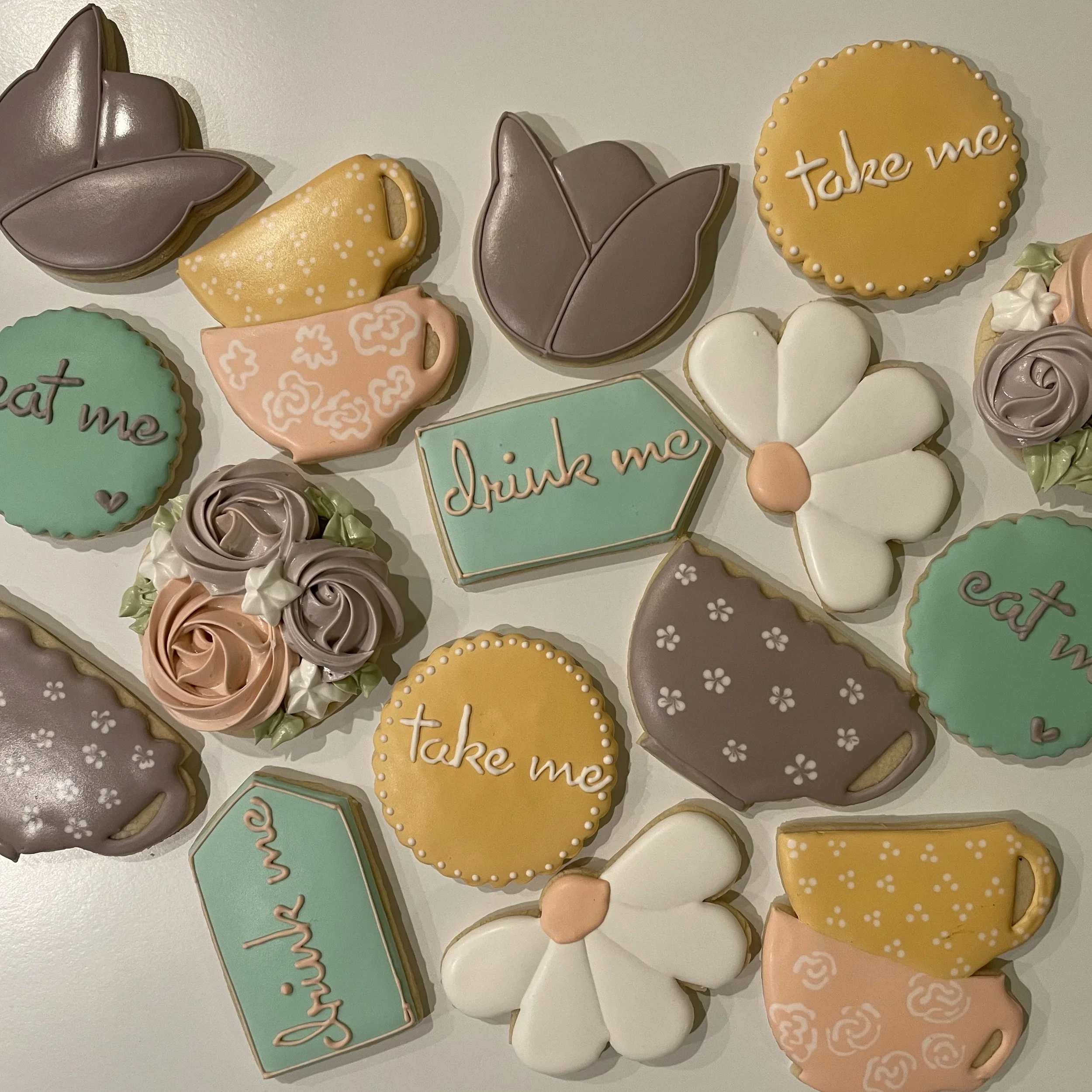 Decorated cookies with messages and images, including an orange cookie with white dots and the words "Take me", a pastel green cookie with writing, and other cookies with floral and swirl designs