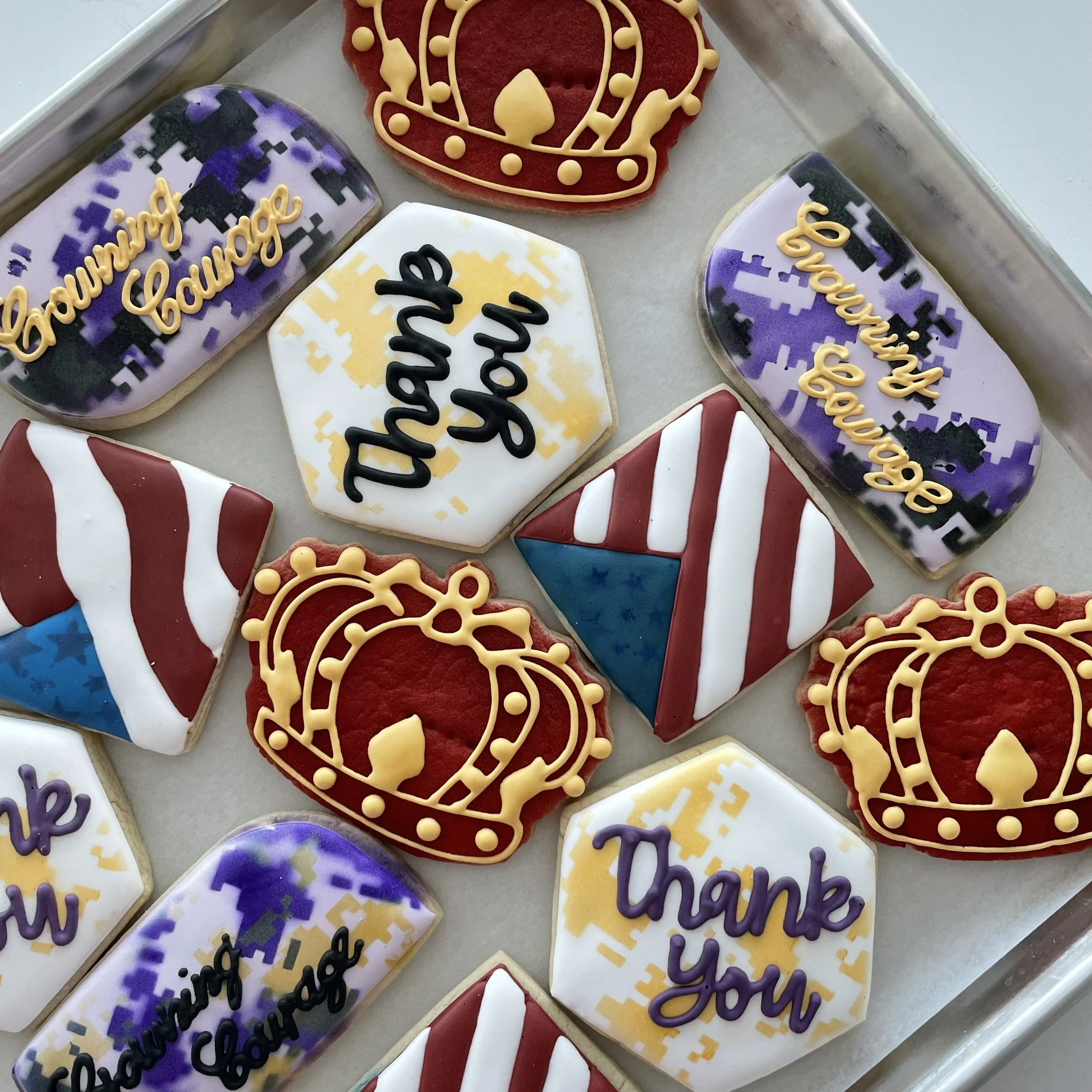 Decorated cookies with celebratory messages and designs, including a crown, a Christmas-themed cookie, and cookies with phrases like 'Daring Dad' and 'Thank You' in colorful icing.