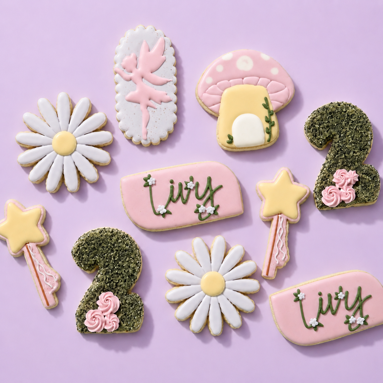 Decorated cookies arranged on a lavender background, including flowers, mushrooms, stars, the number 2, and the name Lily, in pastel pink, yellow, green, white, and black.