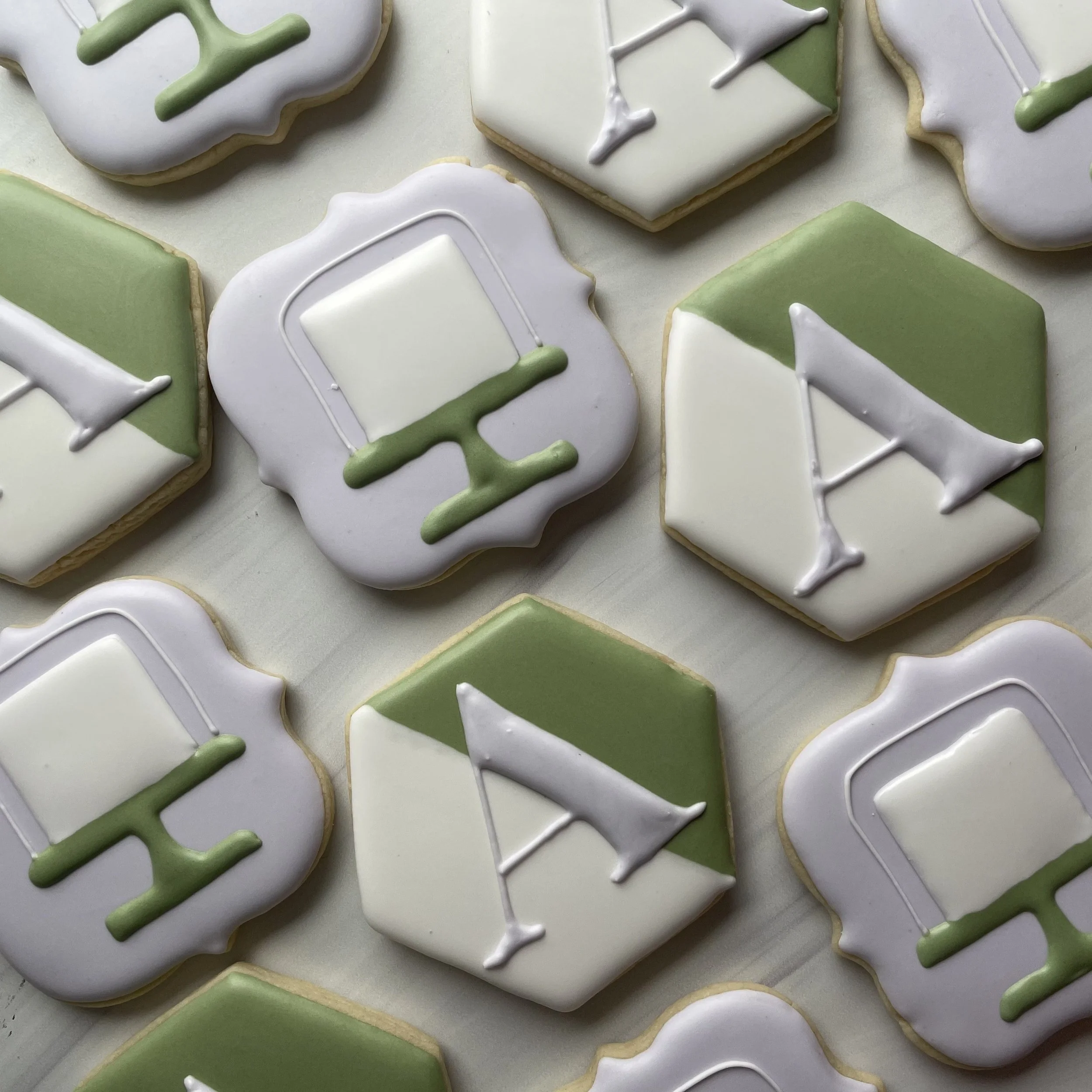 Decorated sugar cookies with green, white, and gray icing, some with holiday or winter-themed designs.
