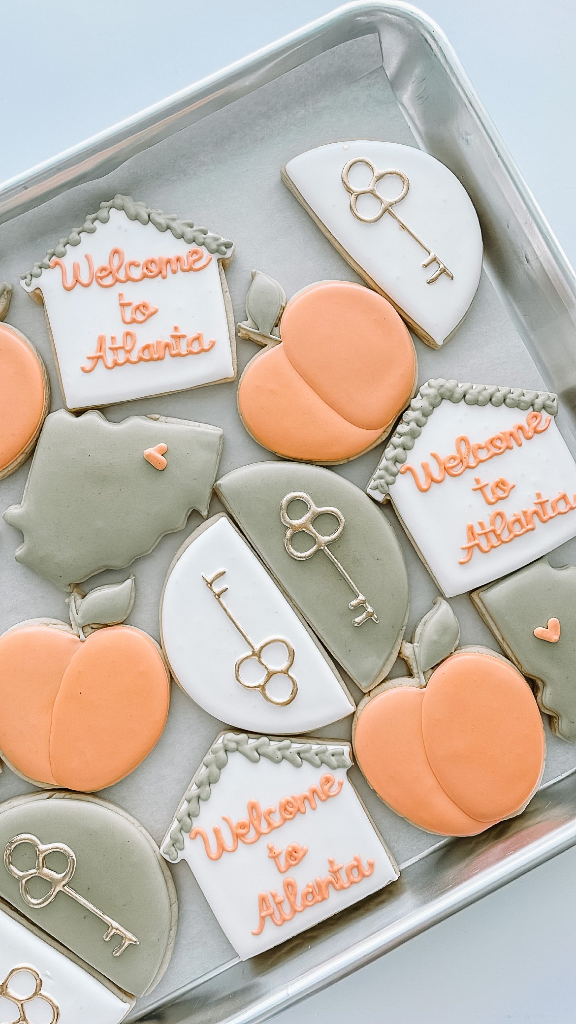 Decorative cookies in the shape of peaches, hearts, and trees, with some cookies featuring the message "Welcome to Atlanta" and others decorated with keys.