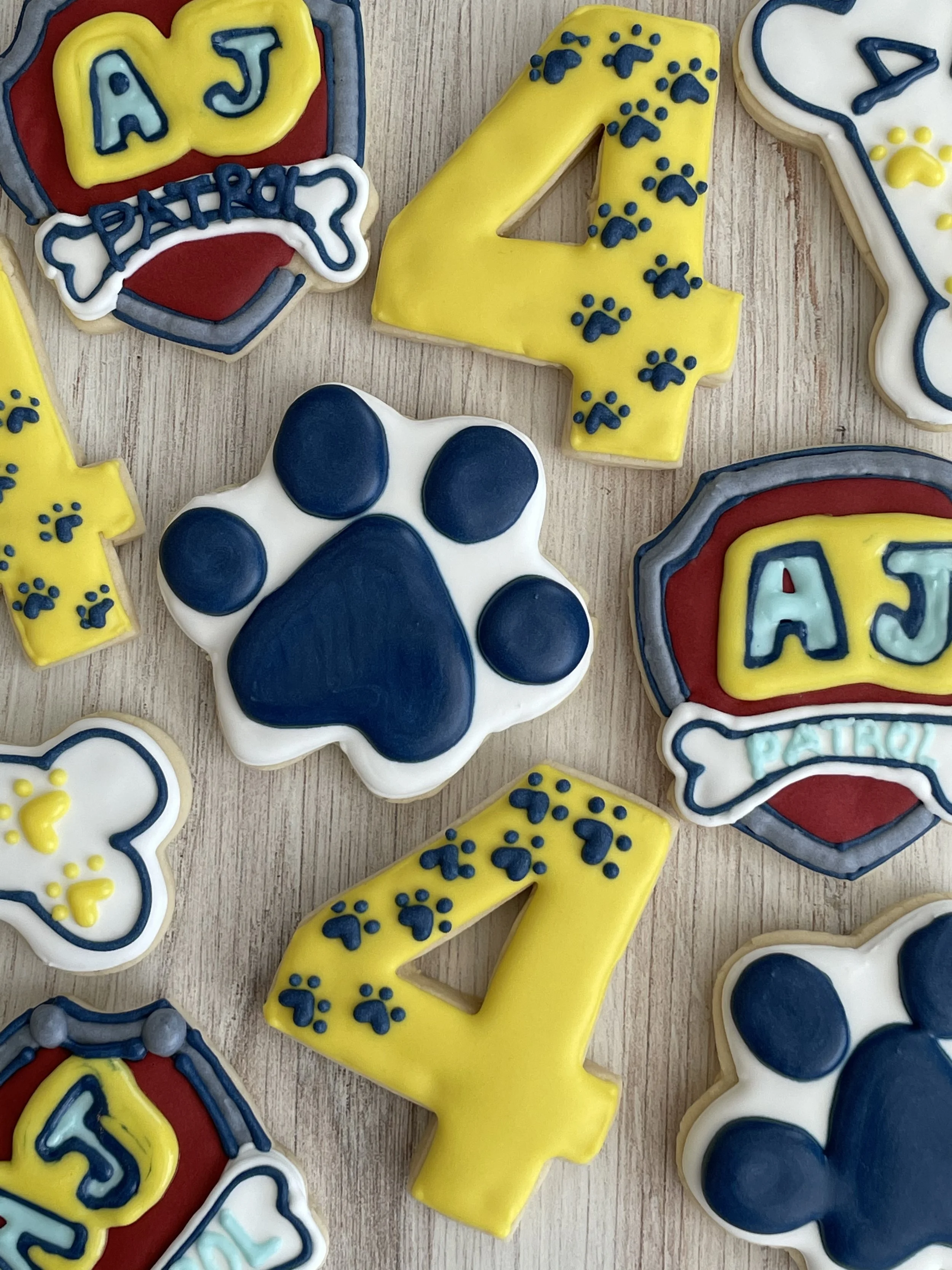 Decorated cookies with puppy paw prints, the number 4, and patches, themed for a dog or puppy birthday celebration.