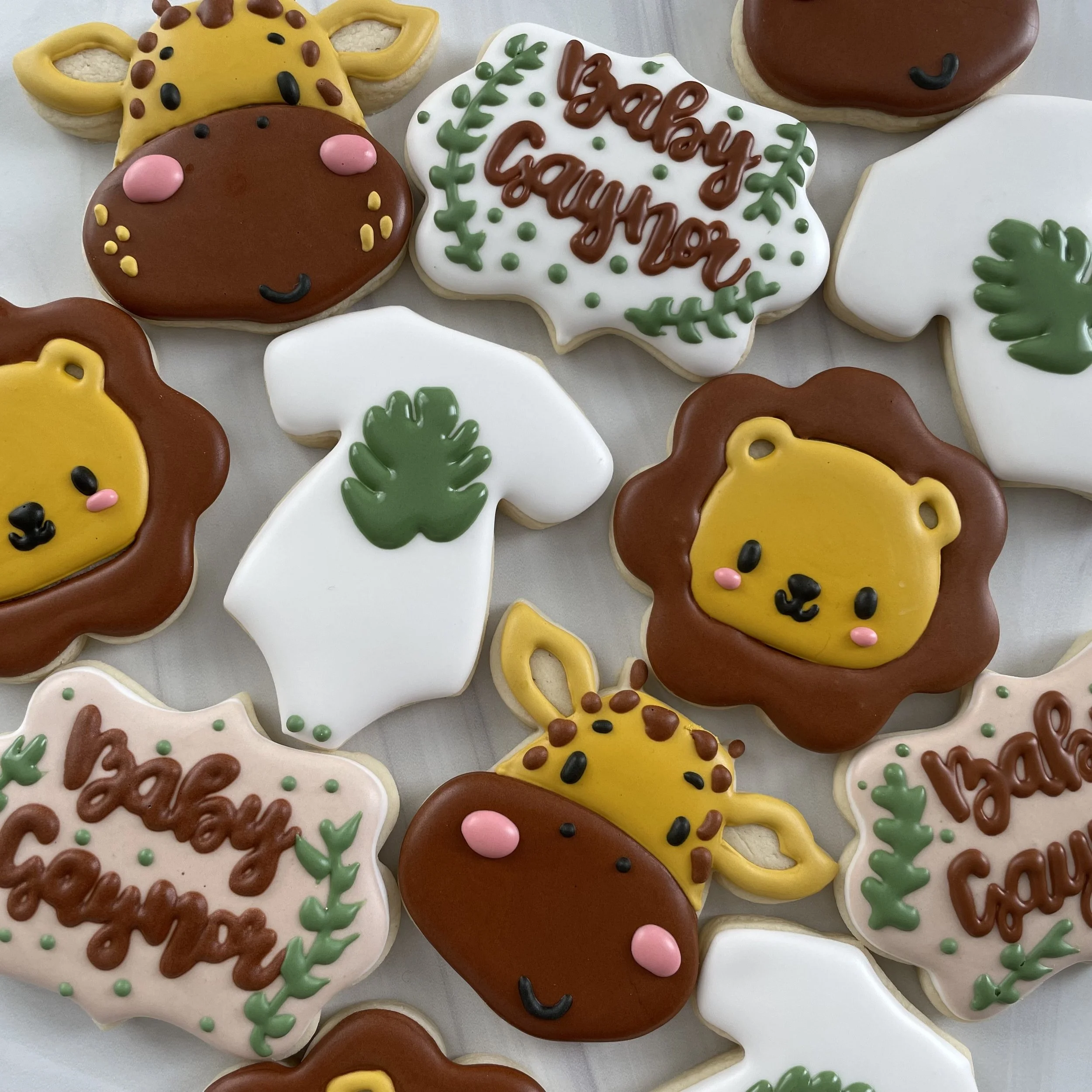 Assorted decorated Christmas cookies with holiday messages and designs, including a cookie with the message "Happy Holidays" written in brown icing surrounded by green decorative icing, and other cookies shaped like animals and holiday symbols.
